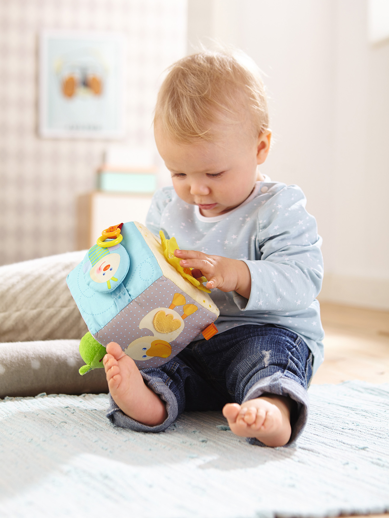 Ein Baby sitzt auf einem Teppich und spielt mit einem Würfelspielzeug mit Enten- und Froschdesign.