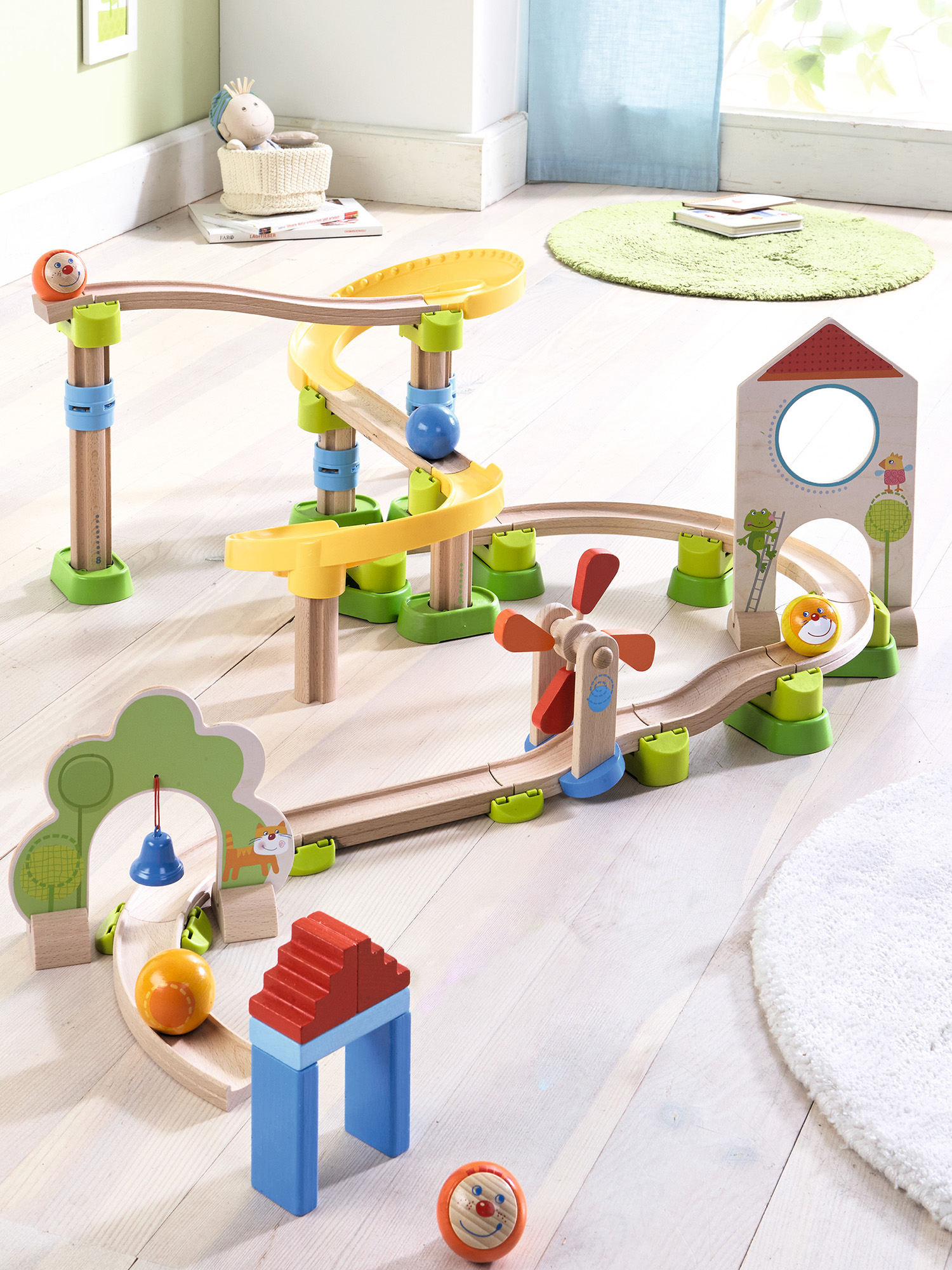 Ein Holzspielzeugbahn-Set mit rollenden Kugeln, einschließlich einer Windmühle, einer Glocke und verschiedenen Strukturen.
