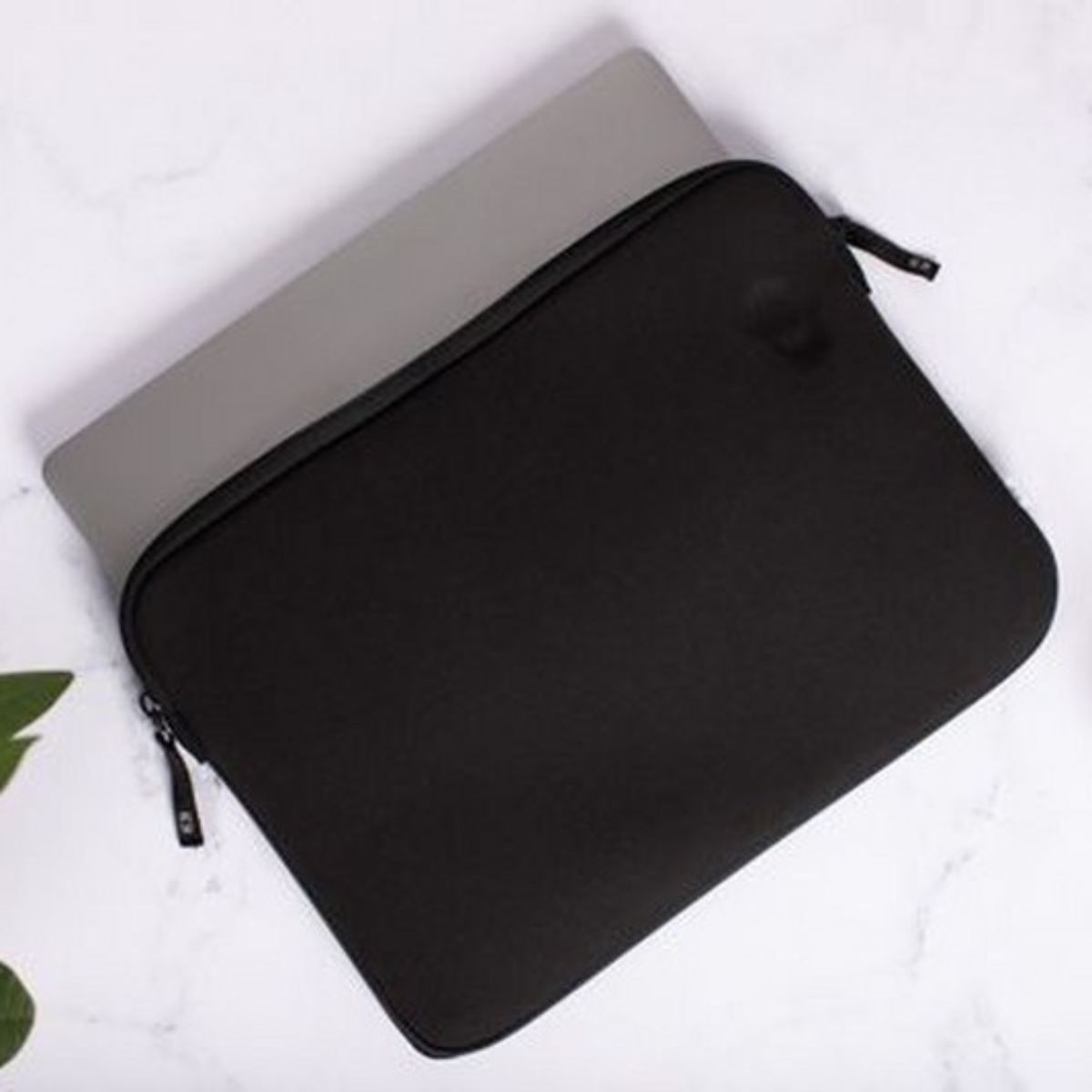 Eine schwarze Laptop-Hülle mit einem Laptop darauf. Die Hülle ist schwarz, der Laptop grau.
