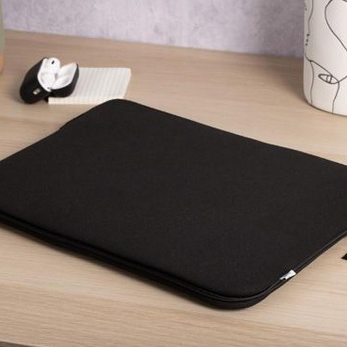 Eine schwarze Laptoptasche liegt auf einem Holztisch, mit Ohrhörern und einem weißen Objekt.