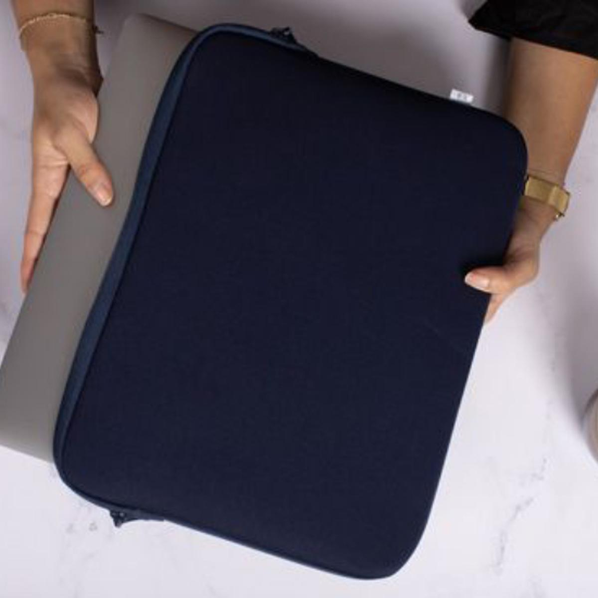 Eine Person hält eine marineblaue Laptoptasche mit Laptop. Der Hintergrund ist eine verschwommene Oberfläche.