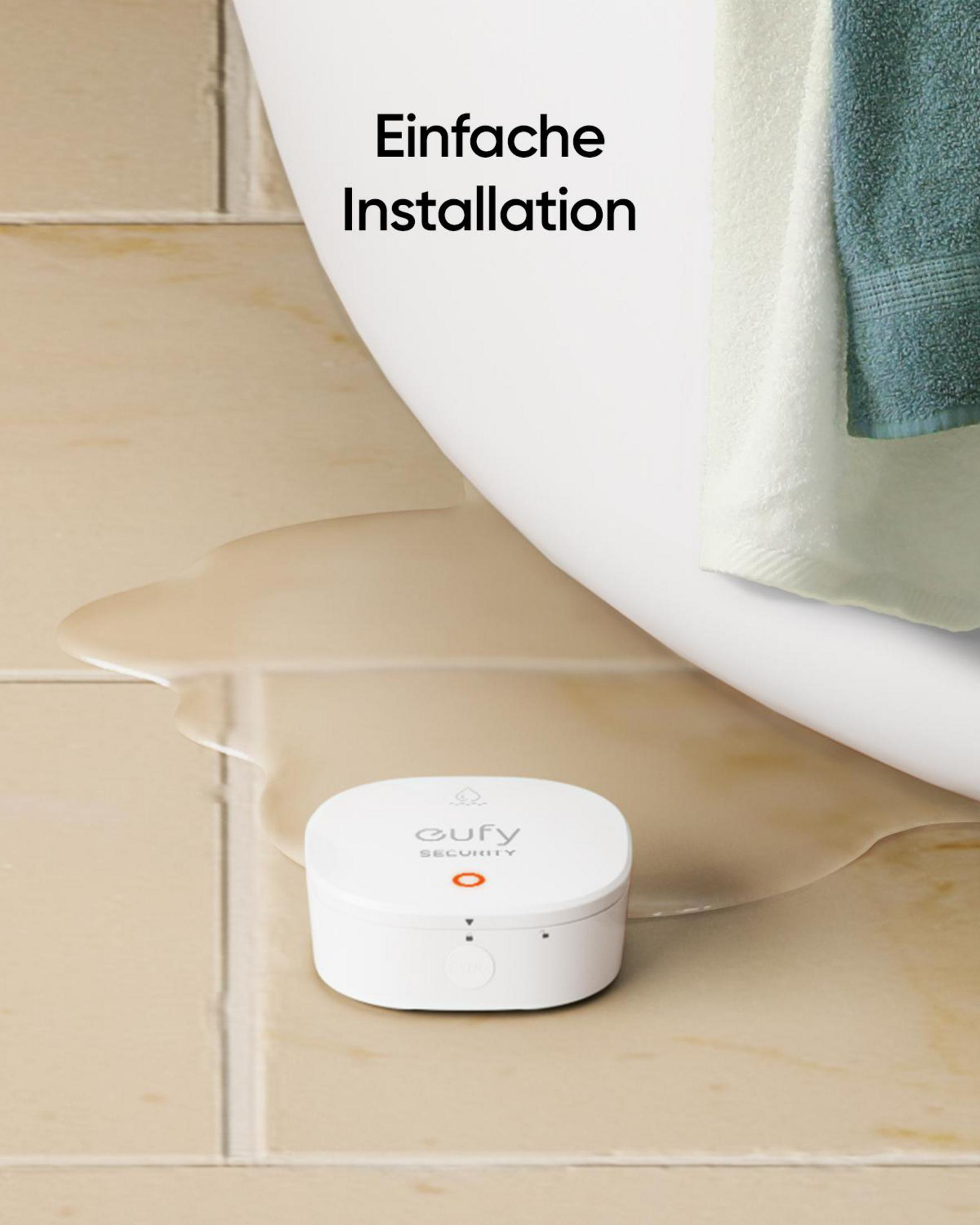 Białe urządzenie zabezpieczające Eufy na płytkach, w pobliżu wanny i rozlanej wody. Tekst: 'Prosta instalacja'.