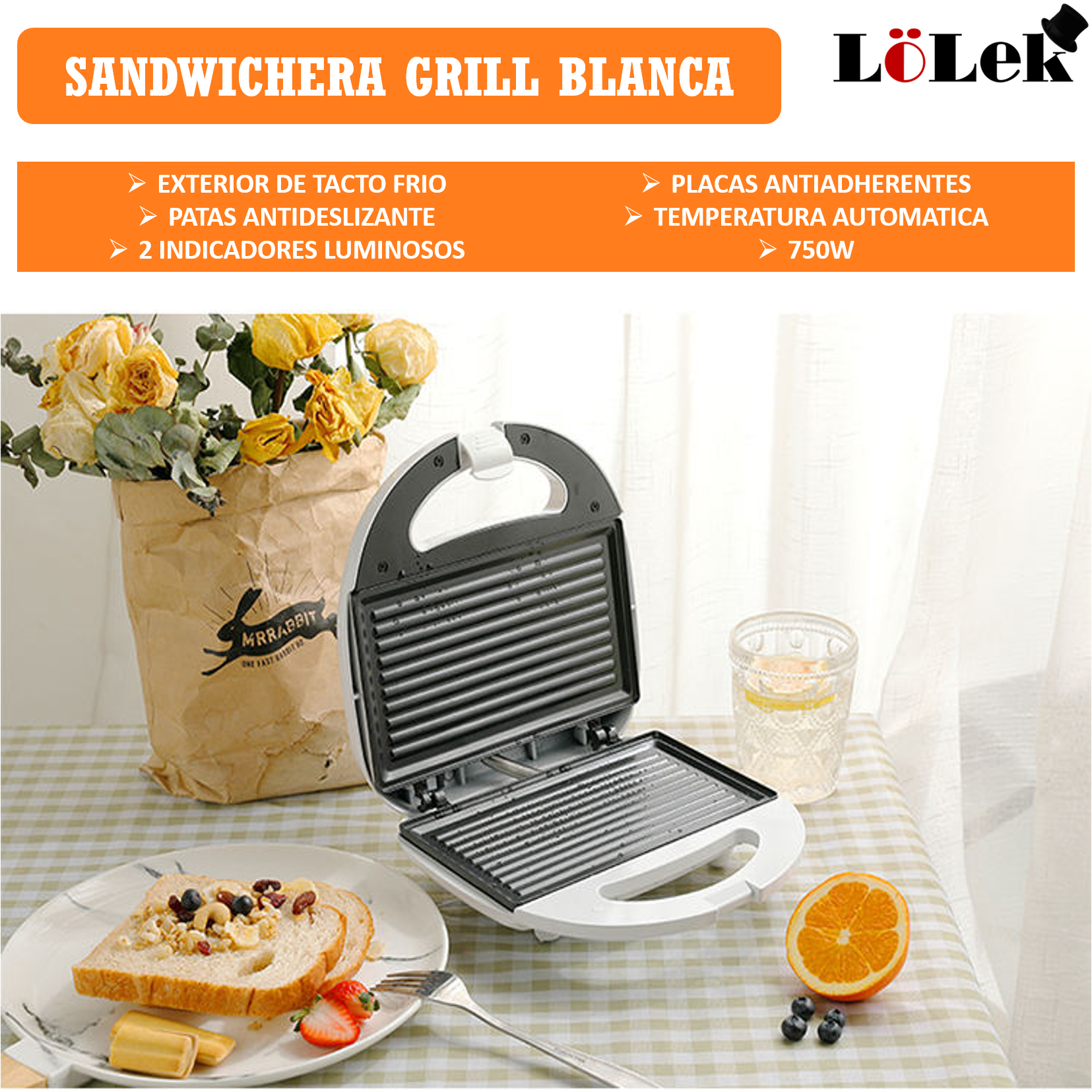 Sandwichera blanca abierta, con sándwiches. Flores y vaso de agua en la mesa. Naranja y fresas en plato.