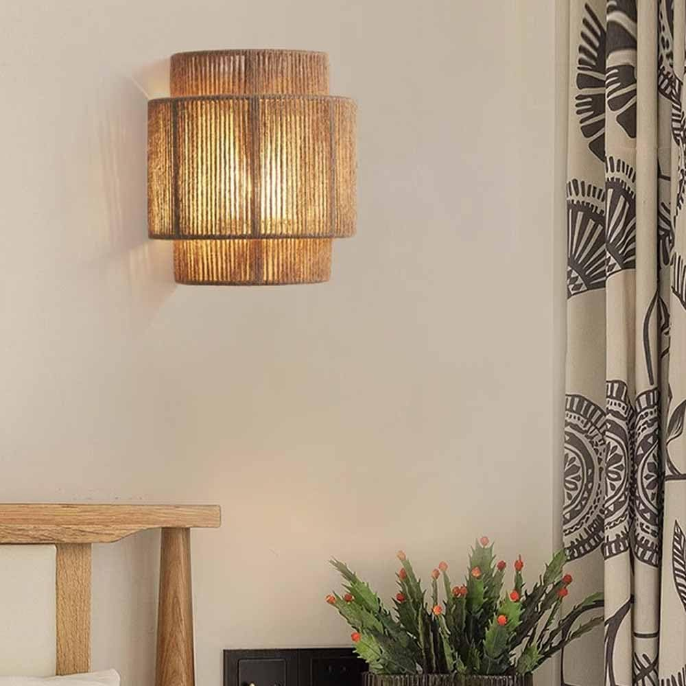 Una lámpara de pared con un diseño tejido en capas, que proyecta un brillo cálido. La luz está montada en una pared neutra.