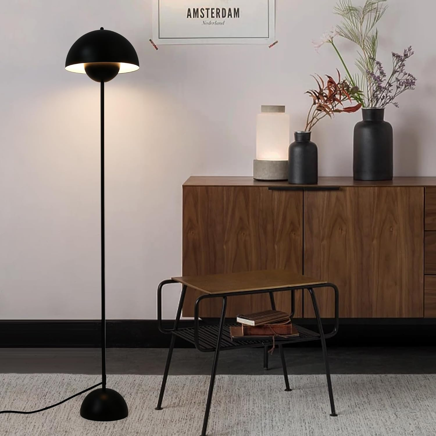 Lámpara de pie negra con pantalla redonda en una habitación con mesa auxiliar y armario.