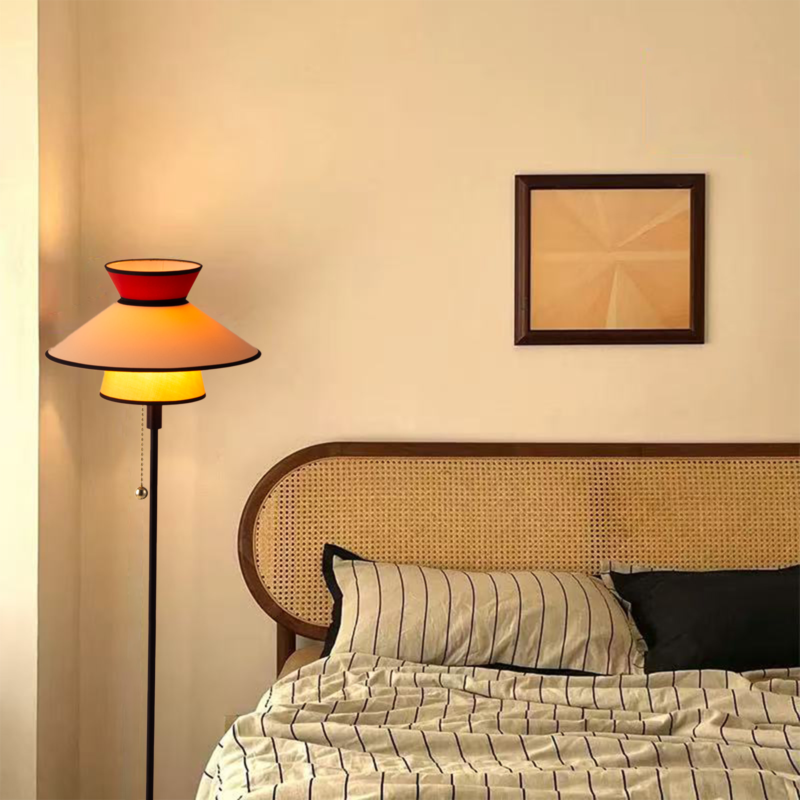Una lámpara de pie con pantalla en capas junto a una cama con cabecero tejido.