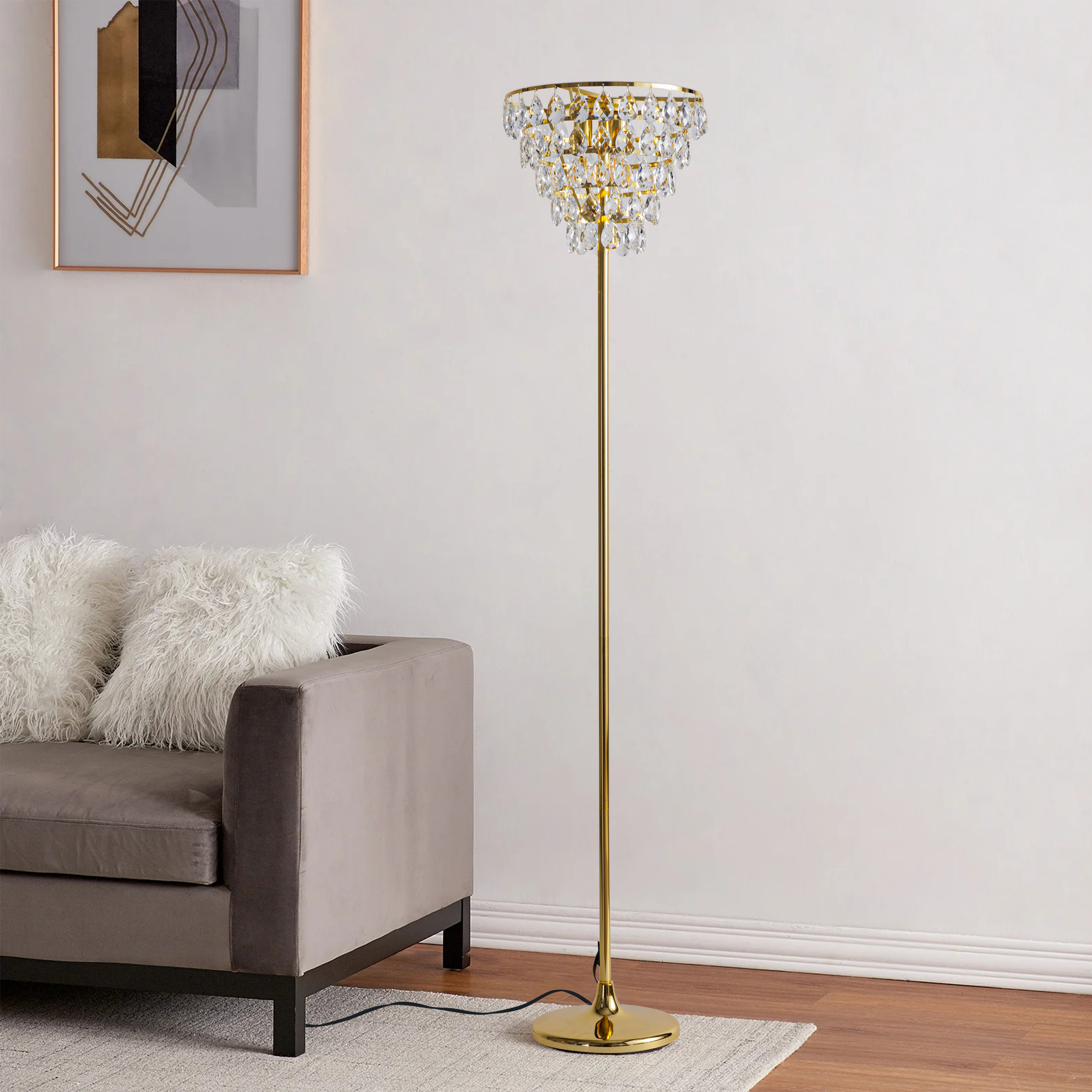 Una lámpara de pie dorada con una parte superior estilo candelabro de cristal, en una habitación con un sofá y una alfombra.