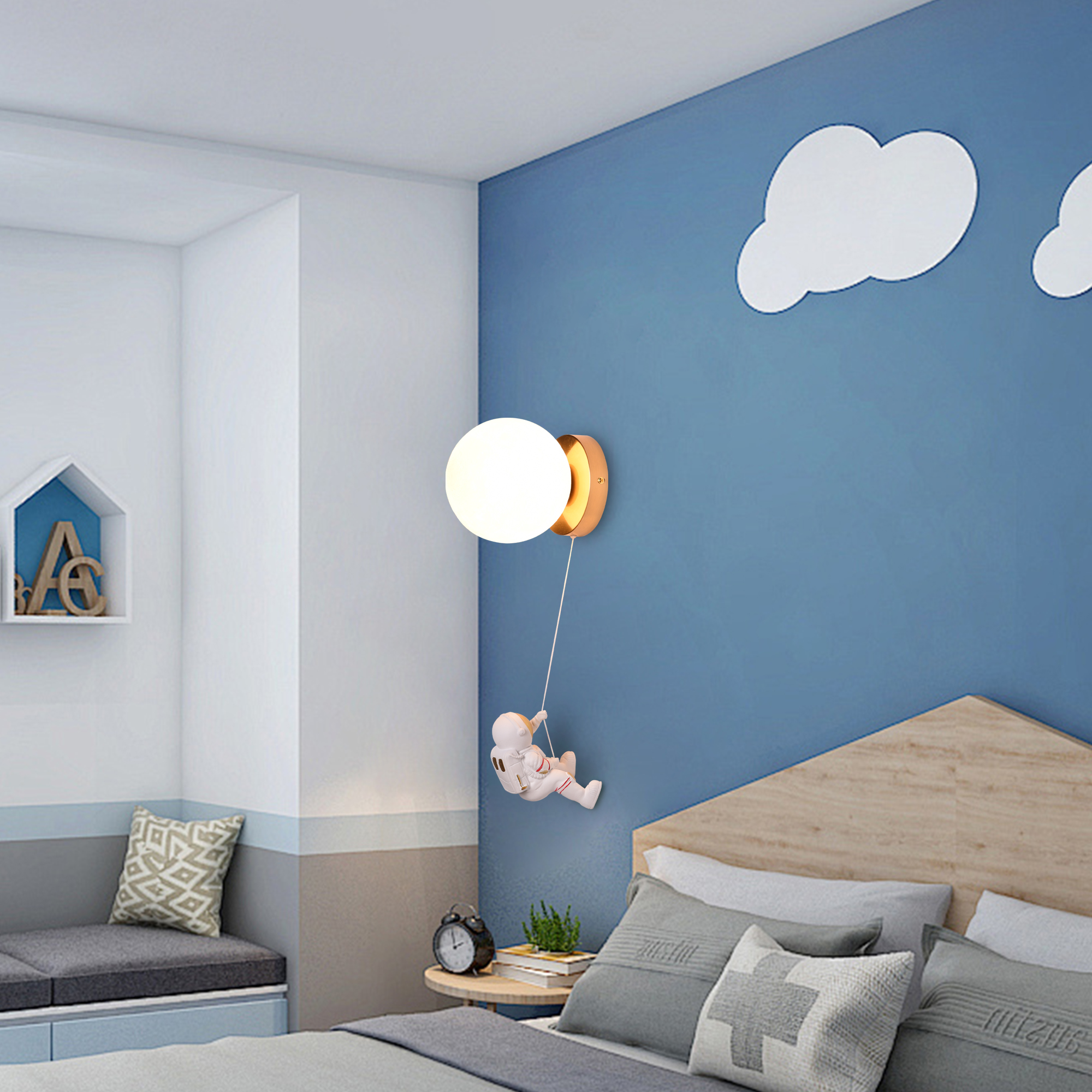 Lámpara de pared con forma de luna y astronauta. Fondo azul con nubes, cama y decoración.