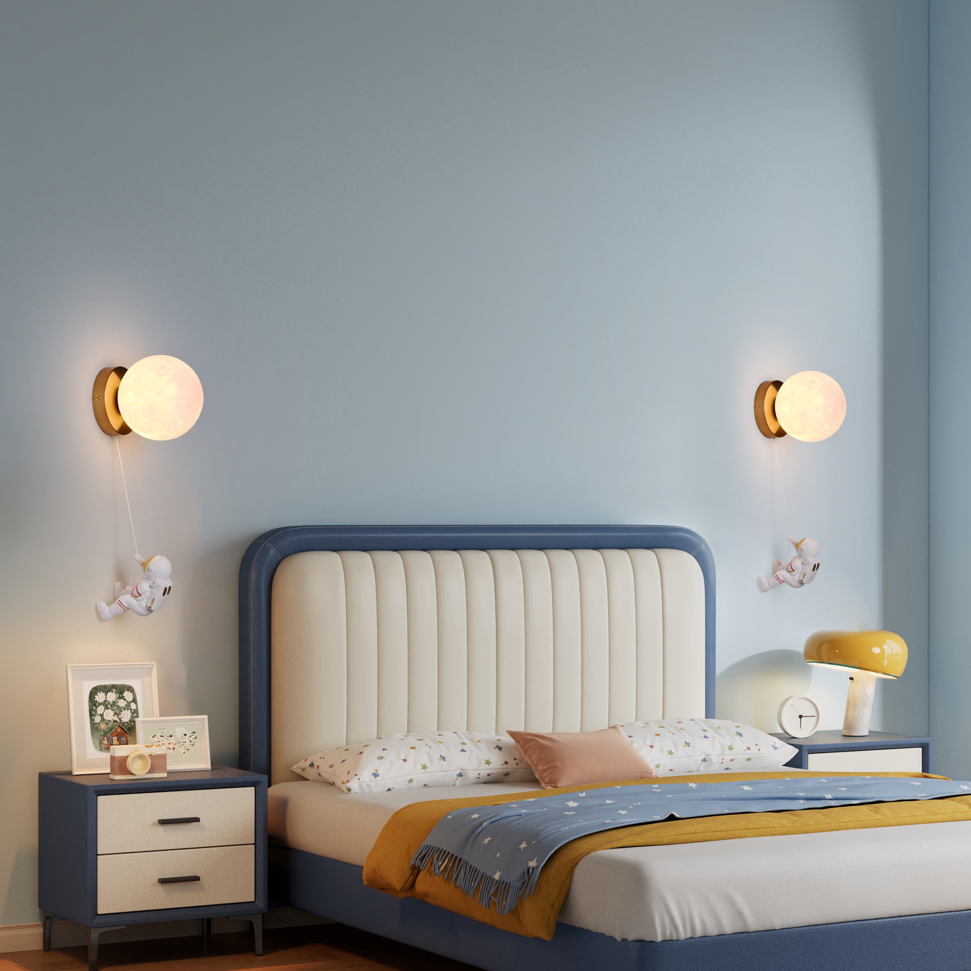 Un dormitorio con pared azul. Dos lámparas de pared, cada una con luz en forma de luna y decoración de astronauta.