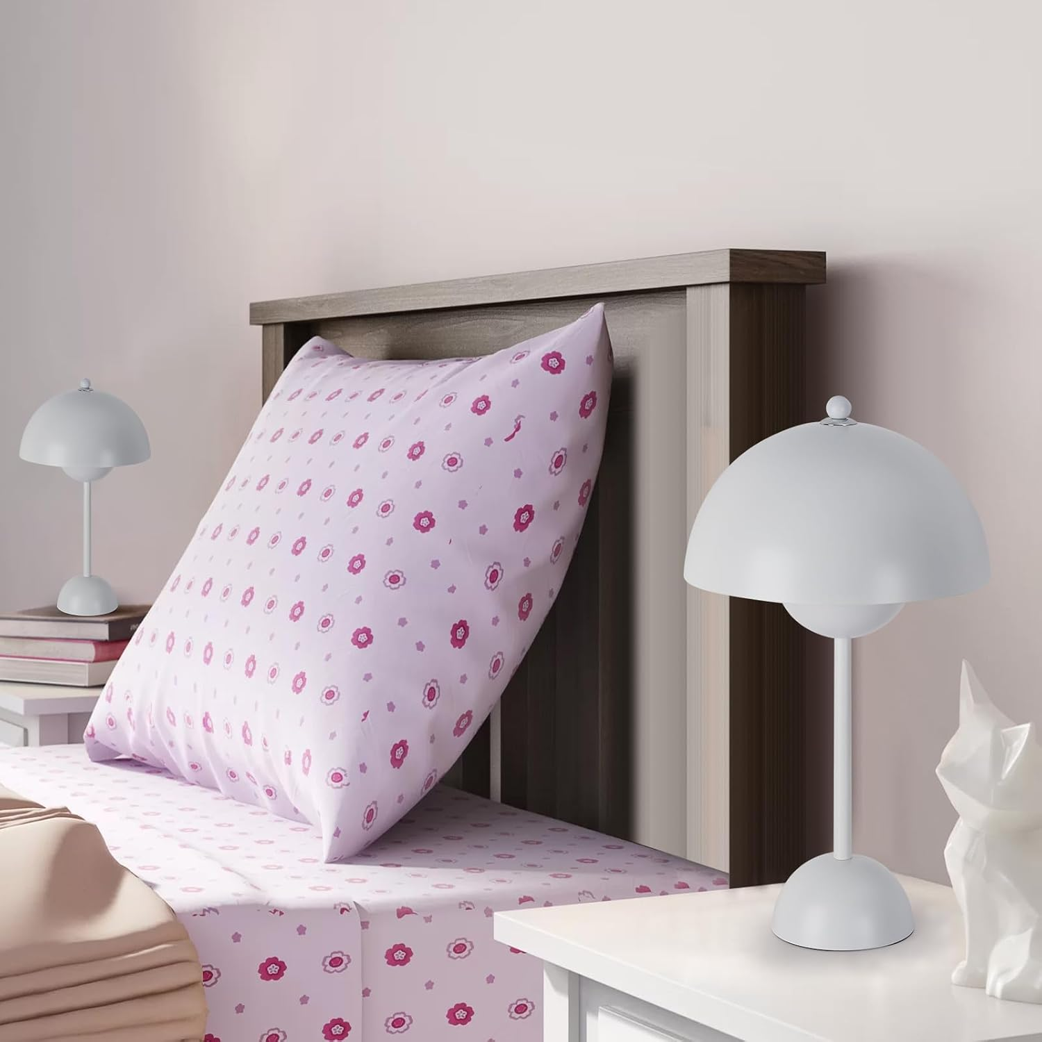 Una cama con una almohada con estampado floral y dos lámparas blancas en las mesitas de noche.