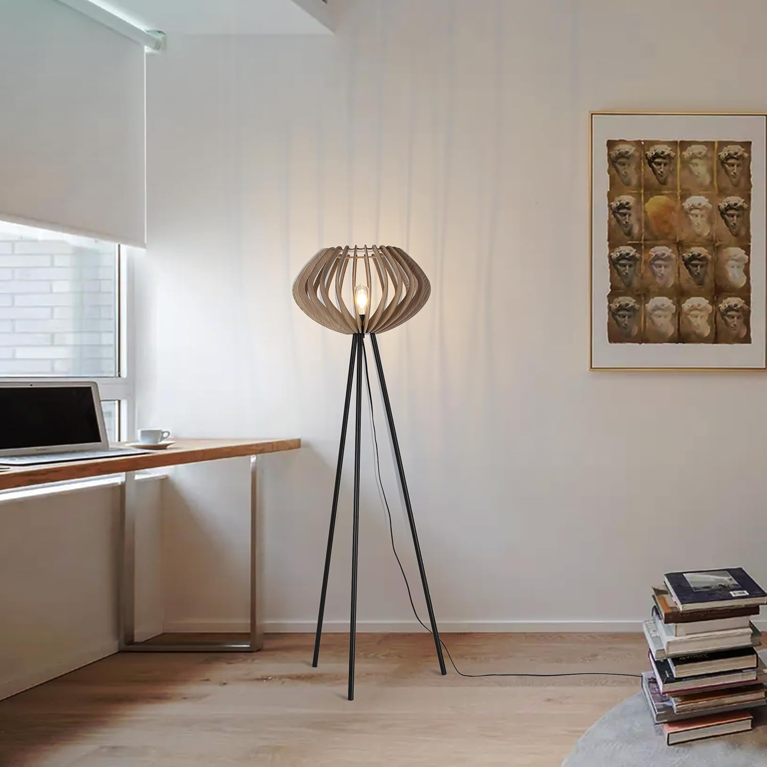 Una habitación con una lámpara de madera con pantalla de madera, encendida, junto a un portátil y pintura.