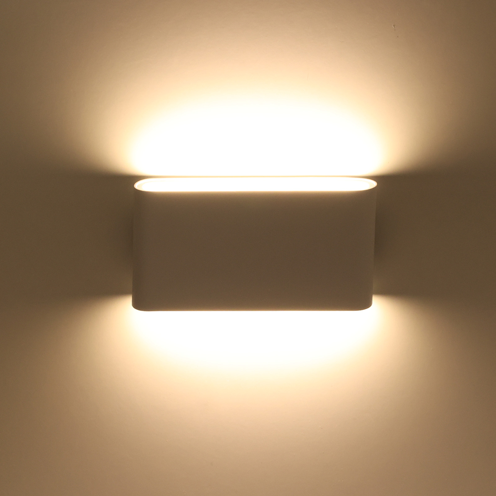Una luz de pared encendida con forma rectangular blanca, proyectando luz hacia arriba y hacia abajo.