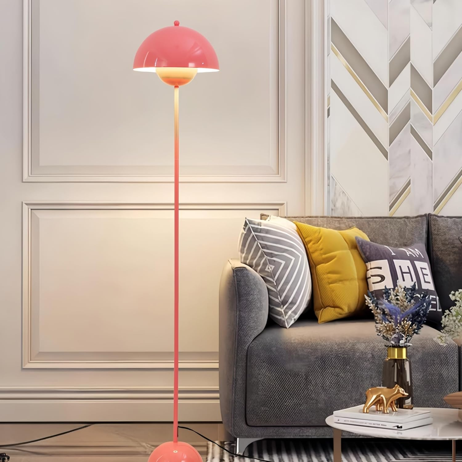 Una lámpara de pie rosa con una pantalla redonda, junto a un sofá, iluminando un salón.