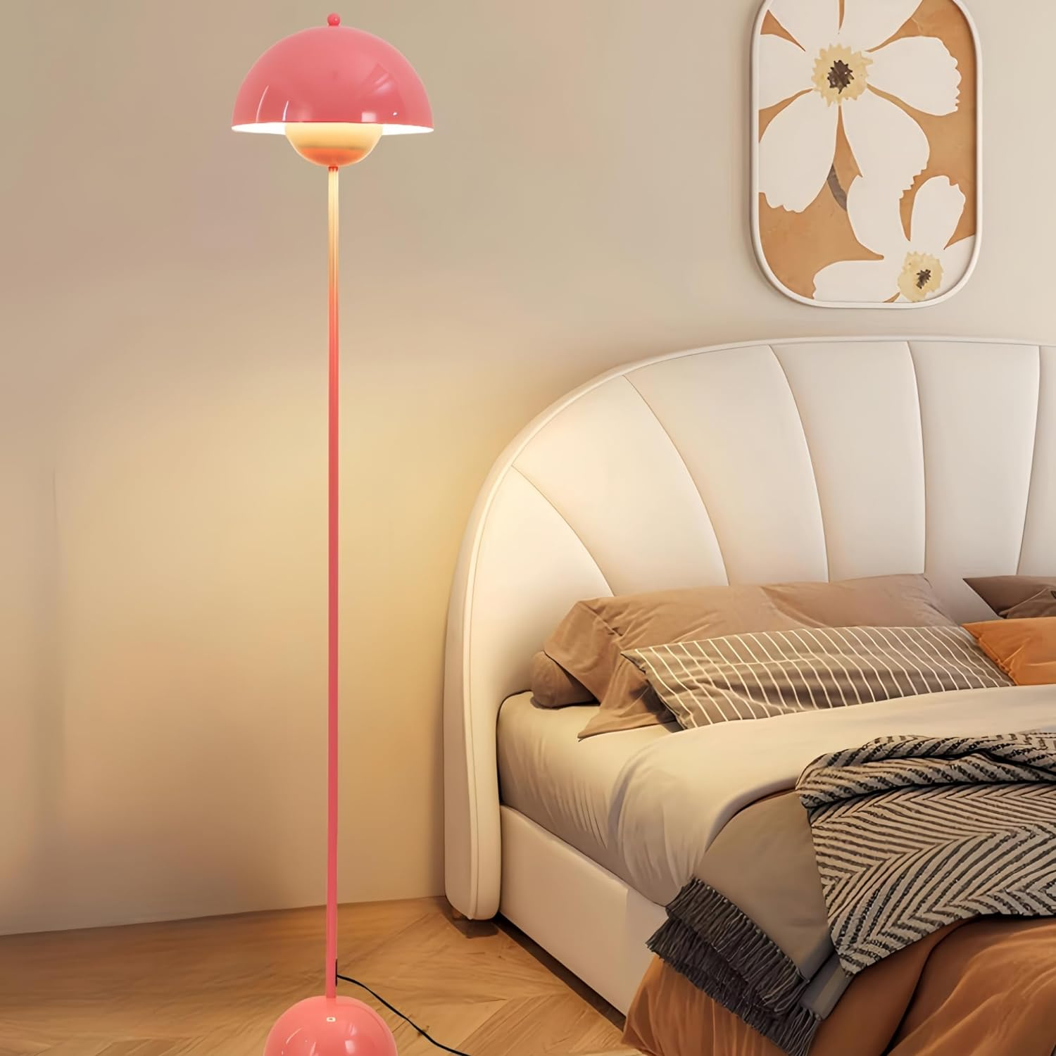 Dormitorio con lámpara de pie rosa, pantalla en forma de hongo y cama. Cabecero blanco y obras de arte en la pared.