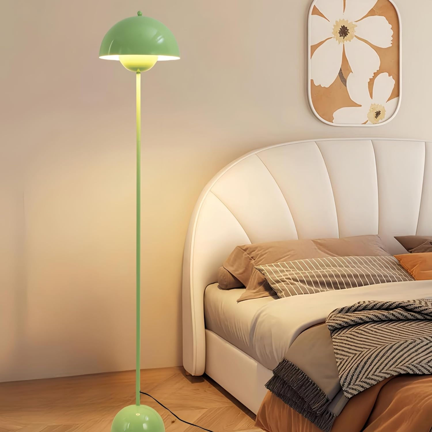 Una lámpara de pie verde en un dormitorio. La lámpara está junto a una cama, con una pintura en la pared.