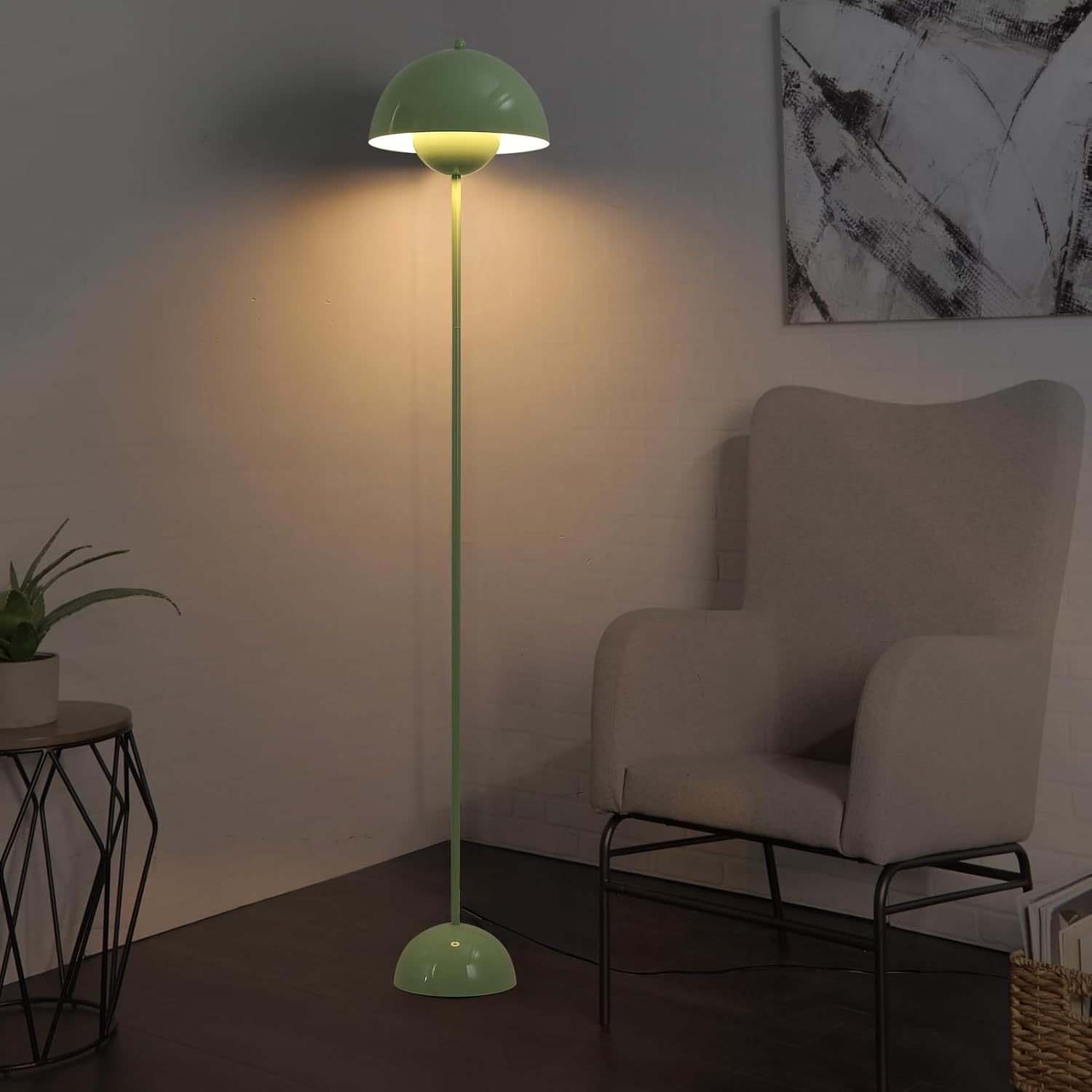 Una lámpara de pie verde en una habitación. Tiene una pantalla en forma de cúpula y está encendida.