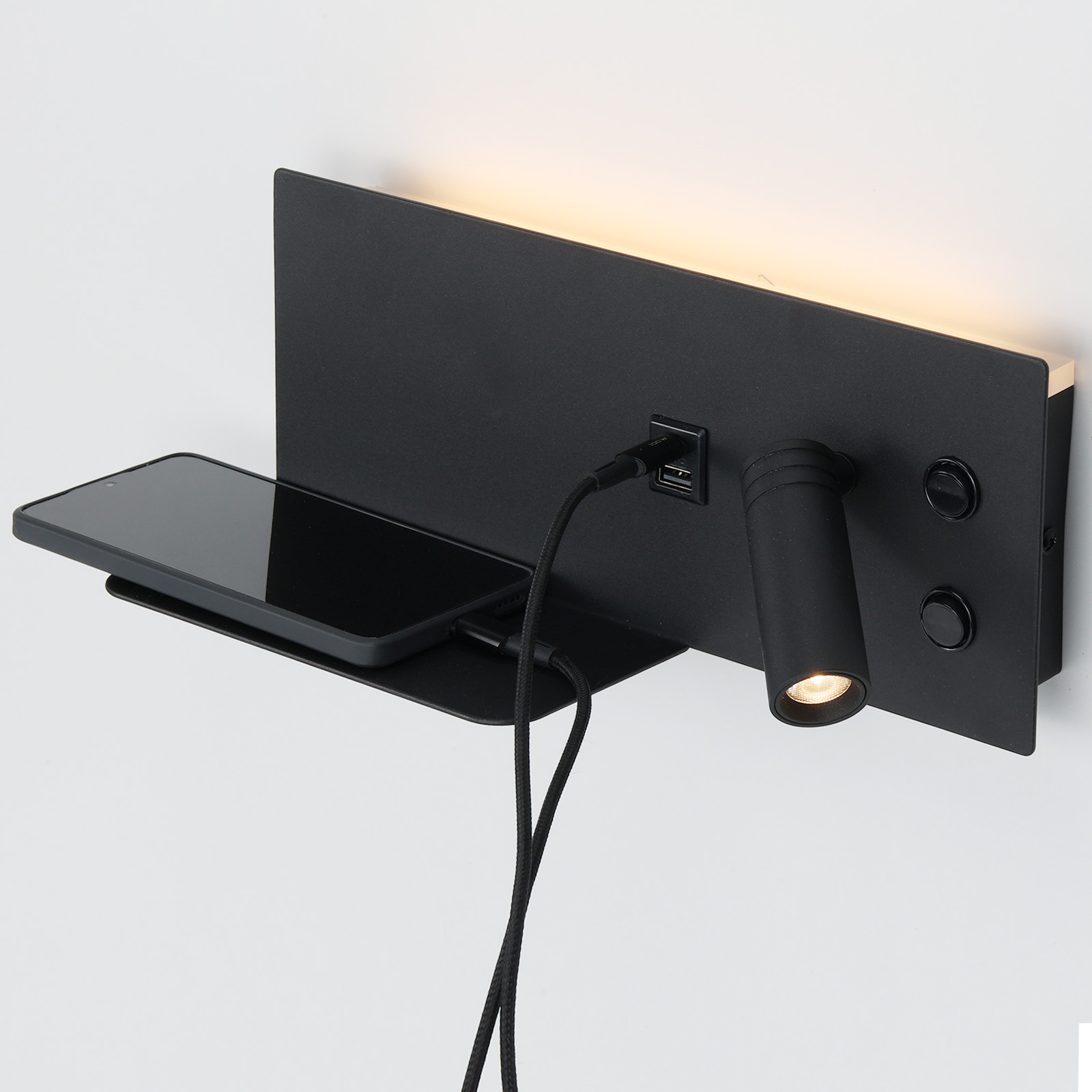 Lámpara de pared negra con estante, smartphone y cable de carga.
