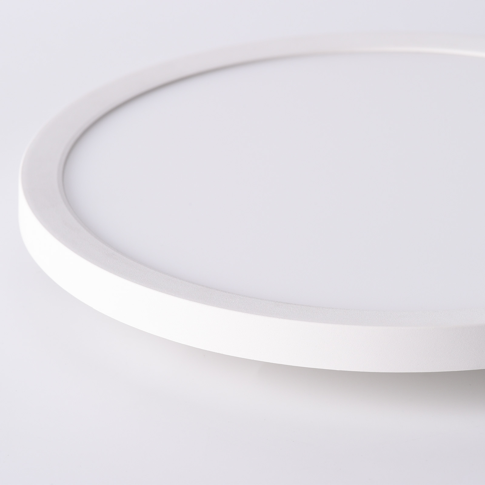 Una luz de techo LED blanca y redonda. La luz está descentrada y tiene un diseño simple y moderno.