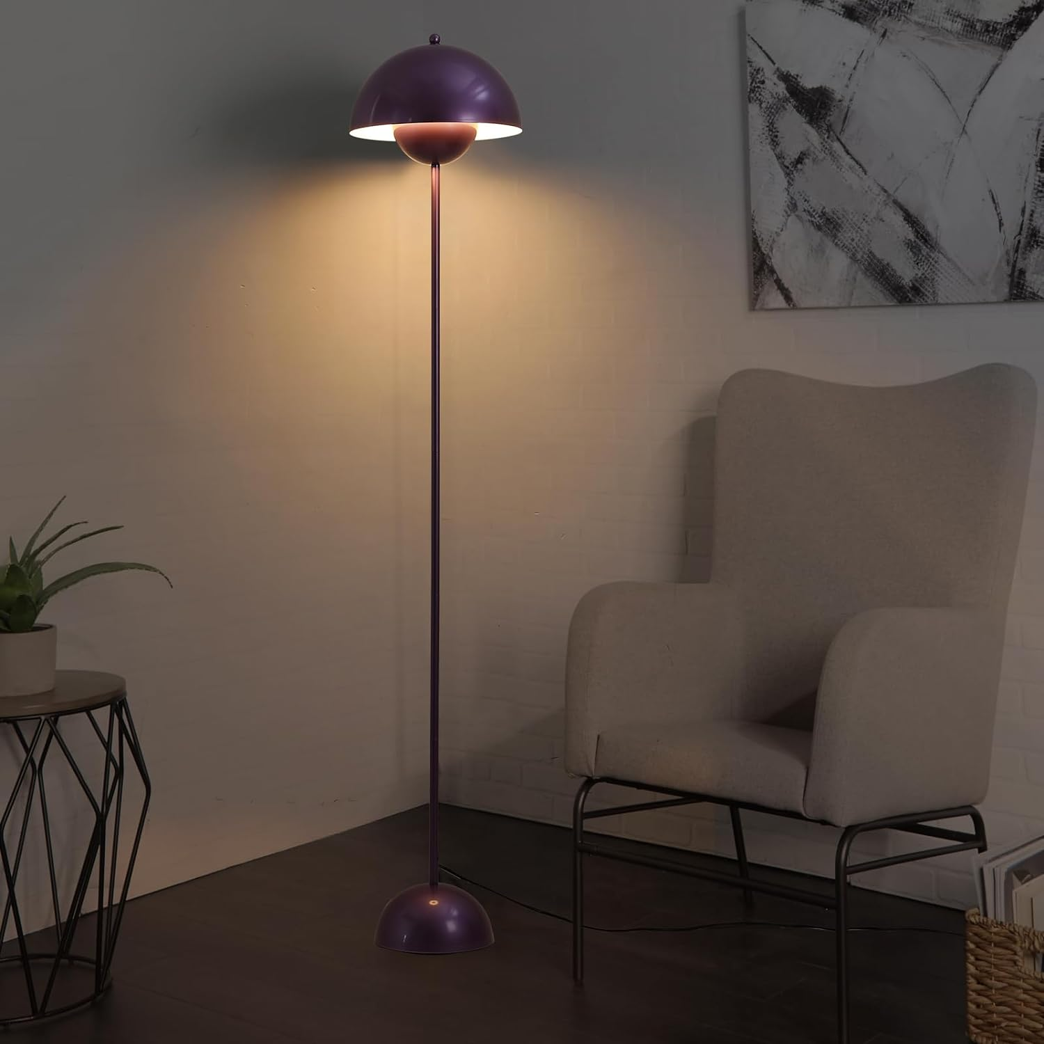 Una lámpara de pie morada junto a una mesa auxiliar, una silla y una obra de arte.