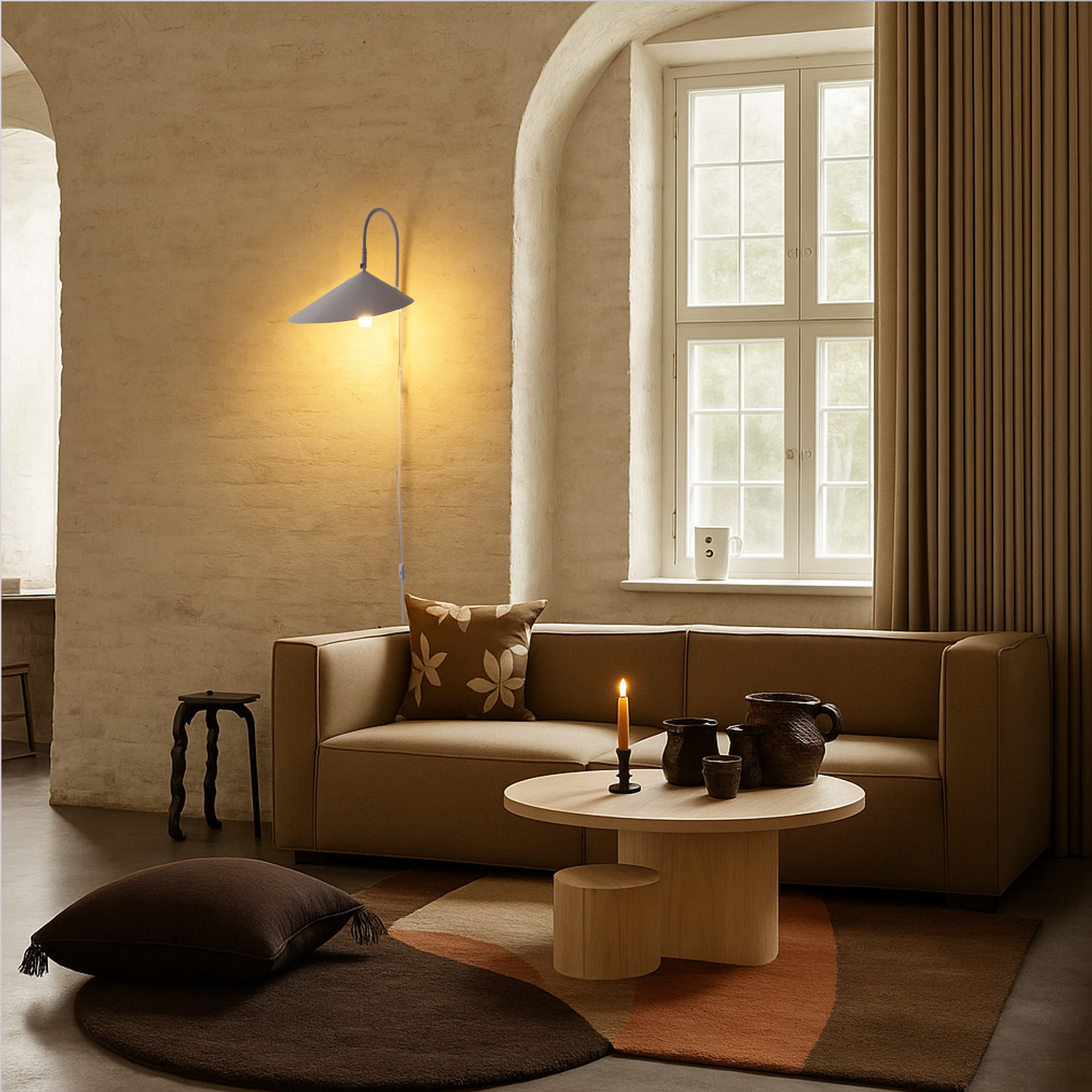 Una sala de estar con lámpara de pared gris, sofá, alfombra y otros elementos decorativos. Una ventana visible.