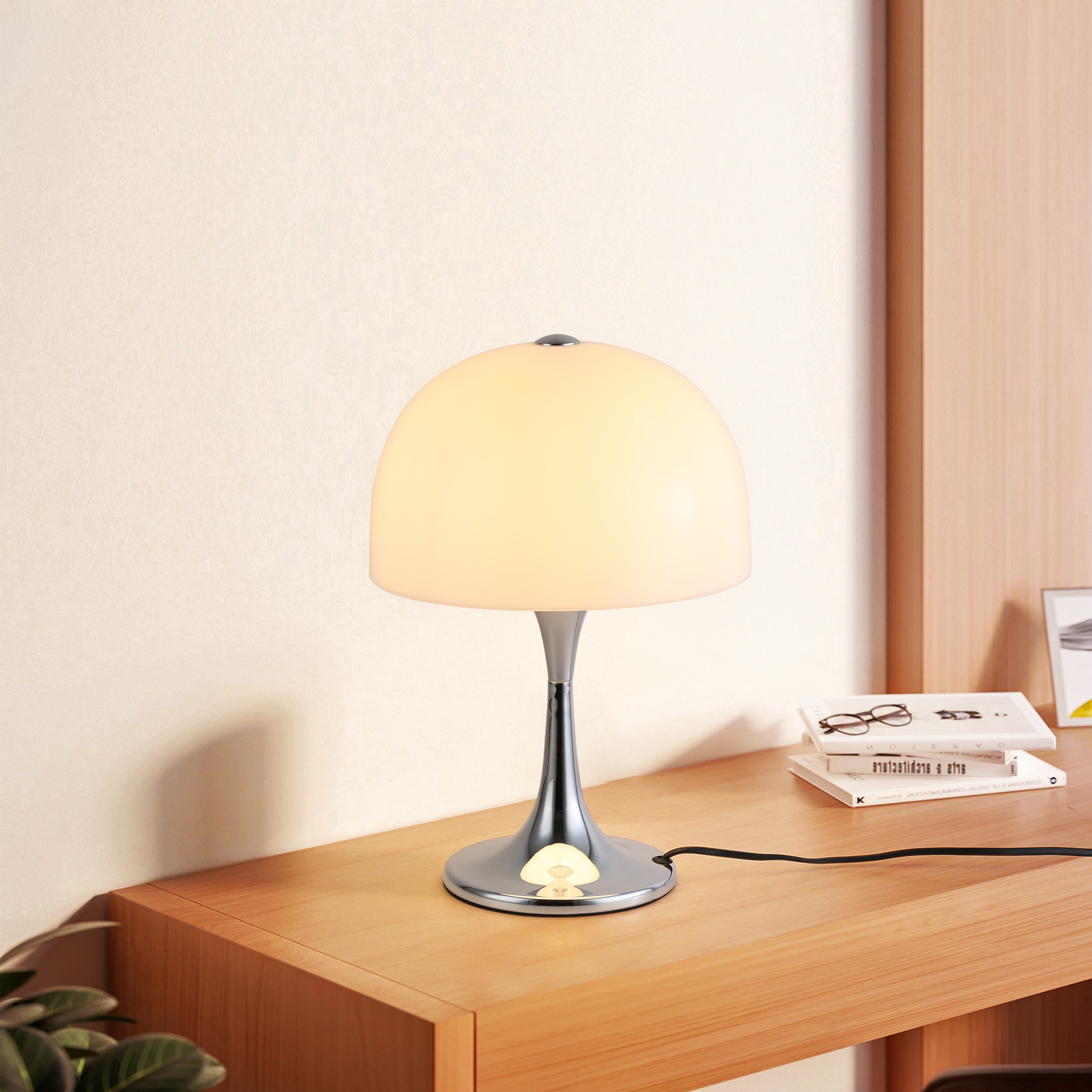 Una elegante lámpara de mesa con base cromada y pantalla blanca en forma de cúpula, sobre un escritorio de madera.