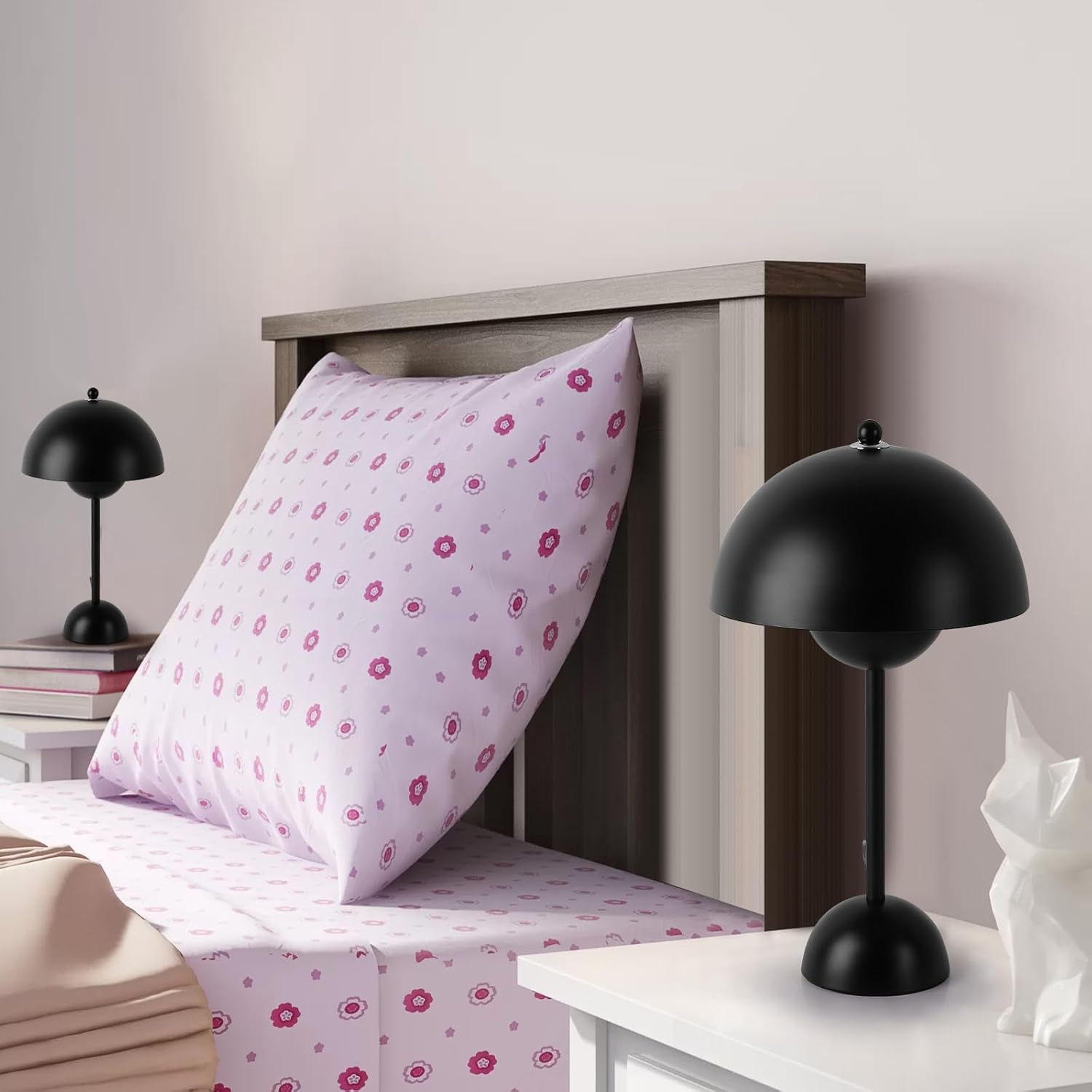 Escena de la cama con dos lámparas negras. Cama con sábanas florales al fondo.