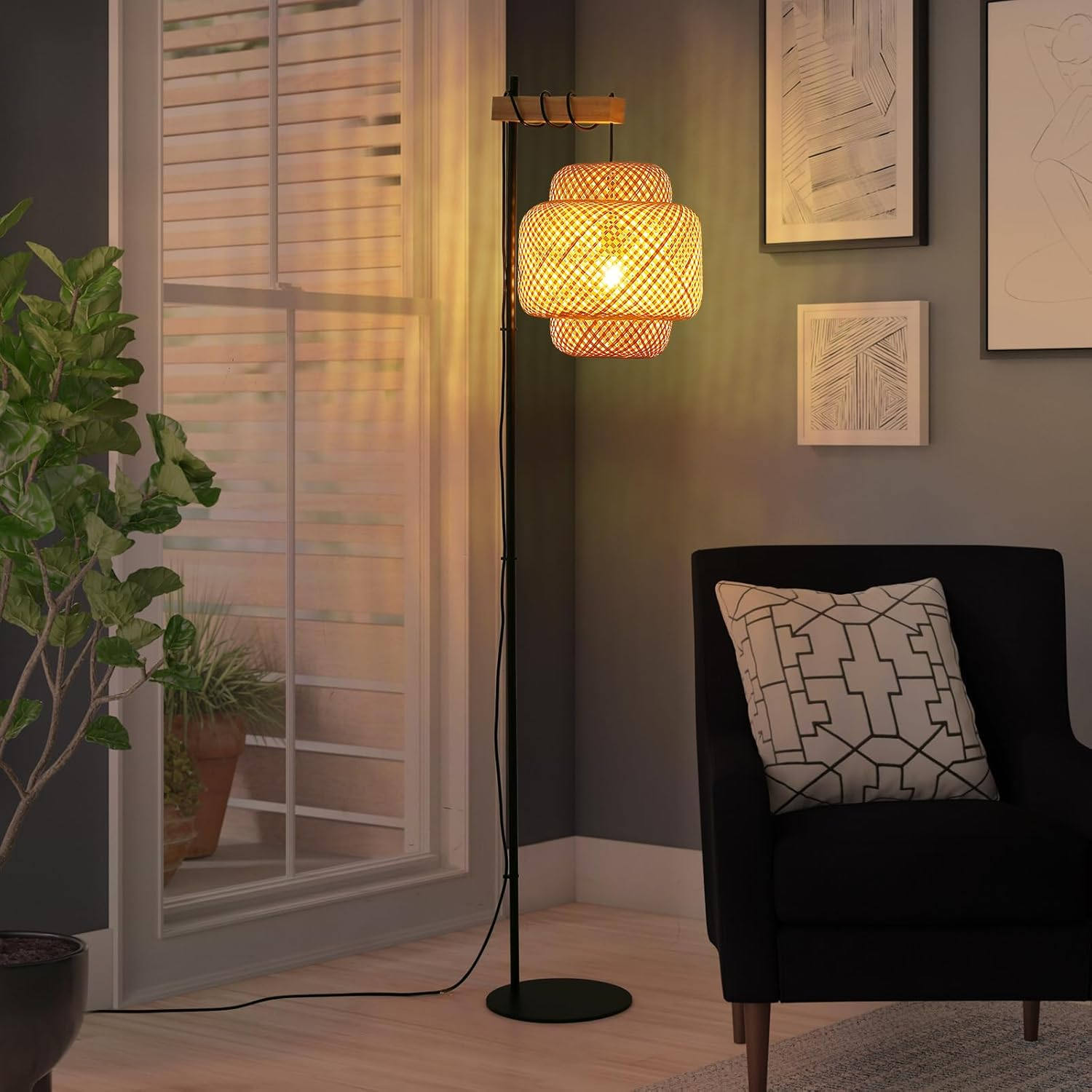 Una lámpara de pie con pantalla tejida en una sala de estar. La lámpara está cerca de una ventana y un sillón negro.