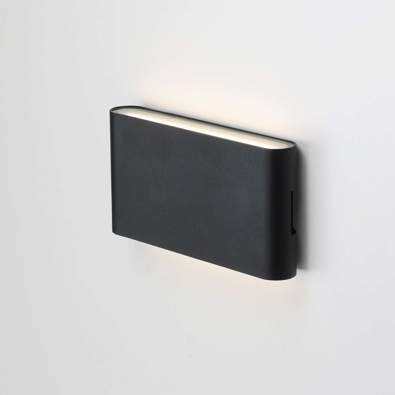 Una lámpara de pared rectangular negra con una tira de luz a lo largo de la parte superior.