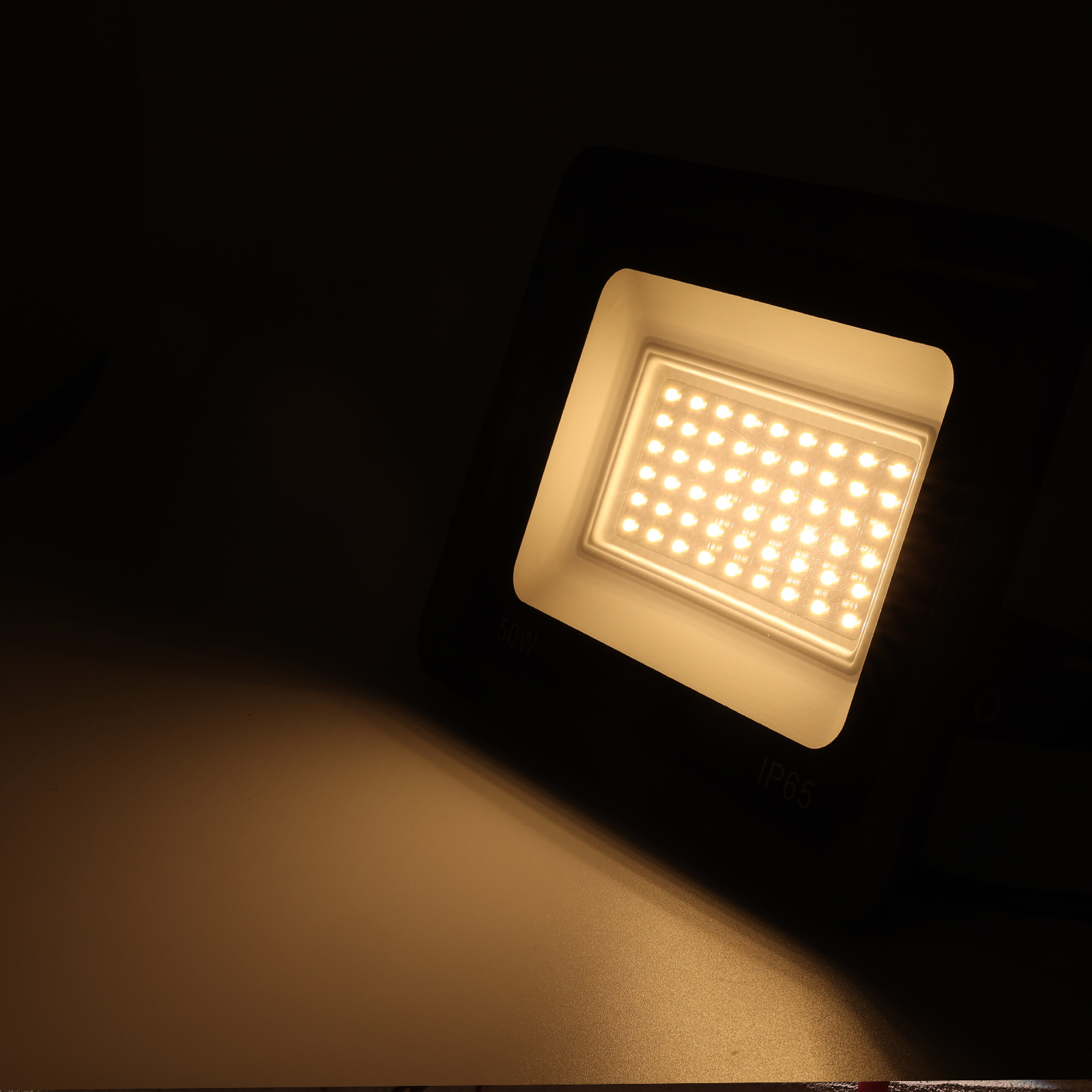 Luz cuadrada negra, encendida, con múltiples luces pequeñas. El fondo es oscuro.