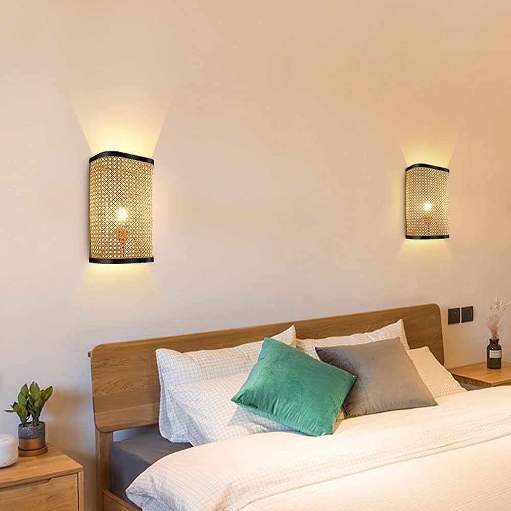 Dos apliques de pared de ratán en una pared. Las luces están encendidas y emitiendo luz.