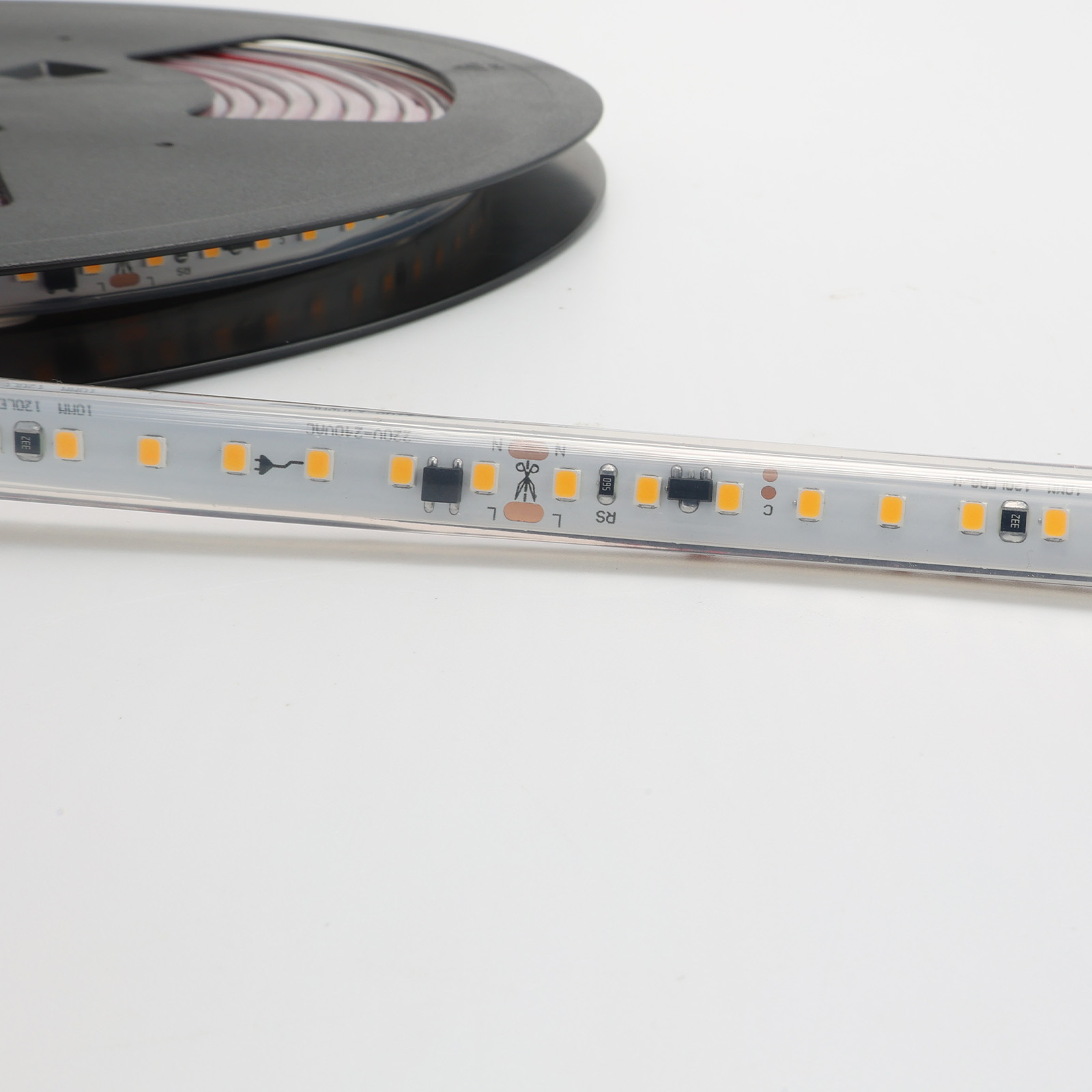 Primer plano de la tira LED, mostrando diodos y marcas. Una bobina está en el fondo.