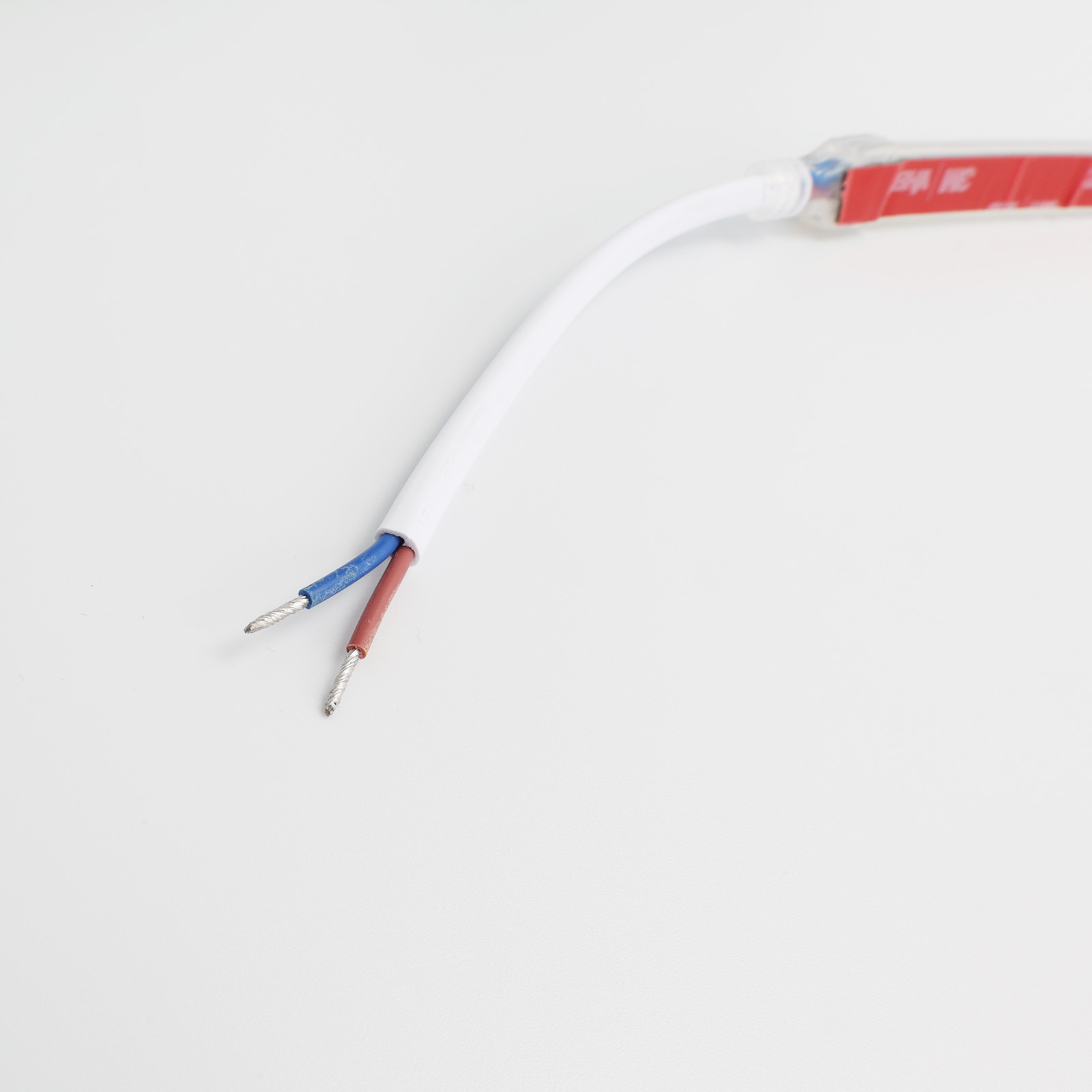 Dos cables, azul y rojo, se extienden desde una carcasa blanca con adhesivo rojo.