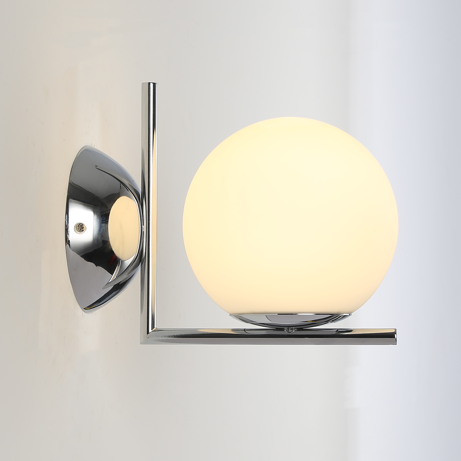Luz montada en la pared con un brazo cromado y una luz de globo blanco.