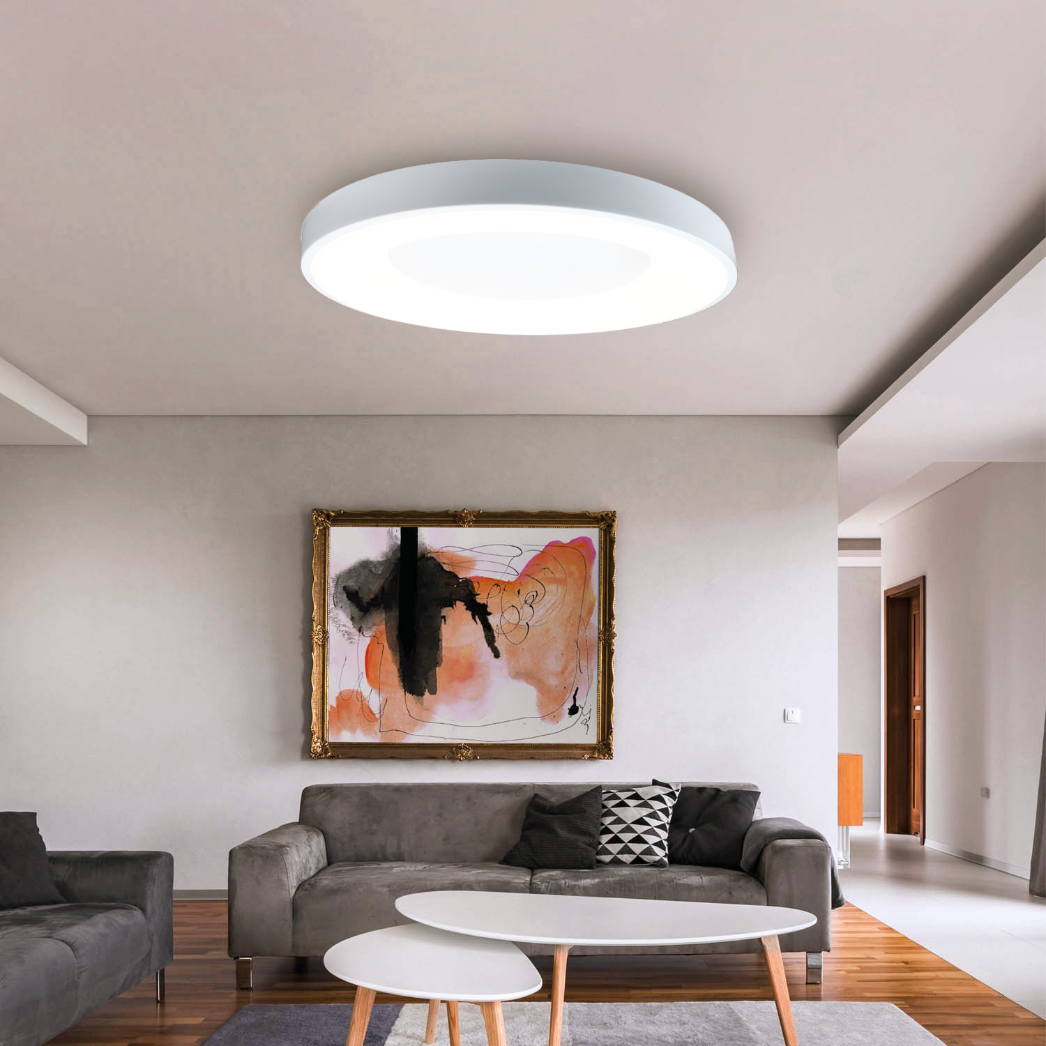 Una sala de estar con lámpara de techo, sofá, mesas de centro y pintura en la pared.