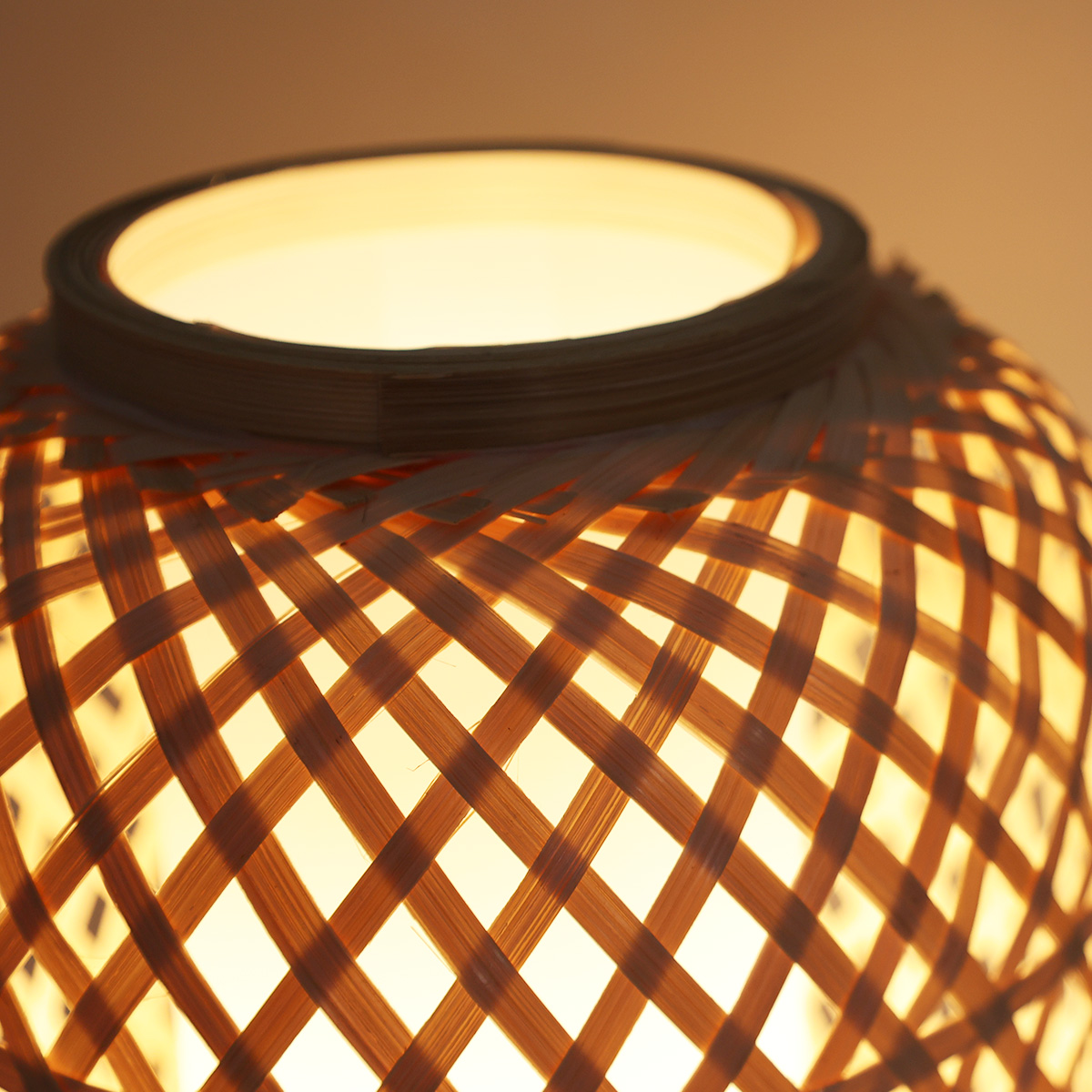 Primer plano del interior iluminado de una lámpara de bambú. La luz brilla a través del tejido.