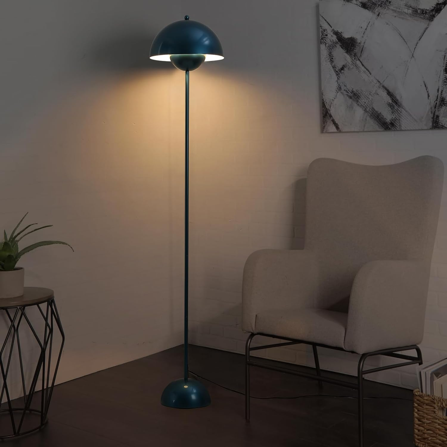 Una lámpara de pie azul en una habitación. Proyecta luz sobre una pared e ilumina una silla.