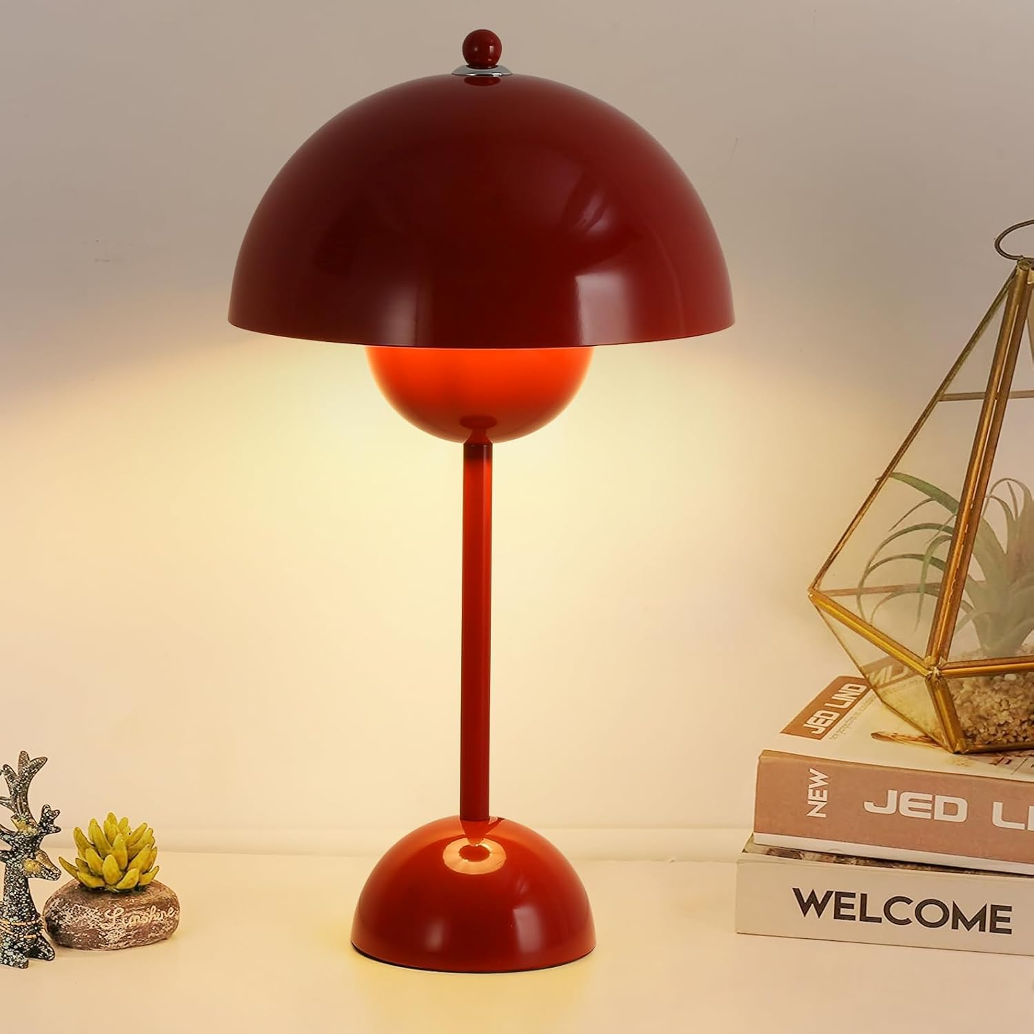 Lámpara de mesa roja con pantalla en forma de cúpula y base redonda, sobre mesa blanca.