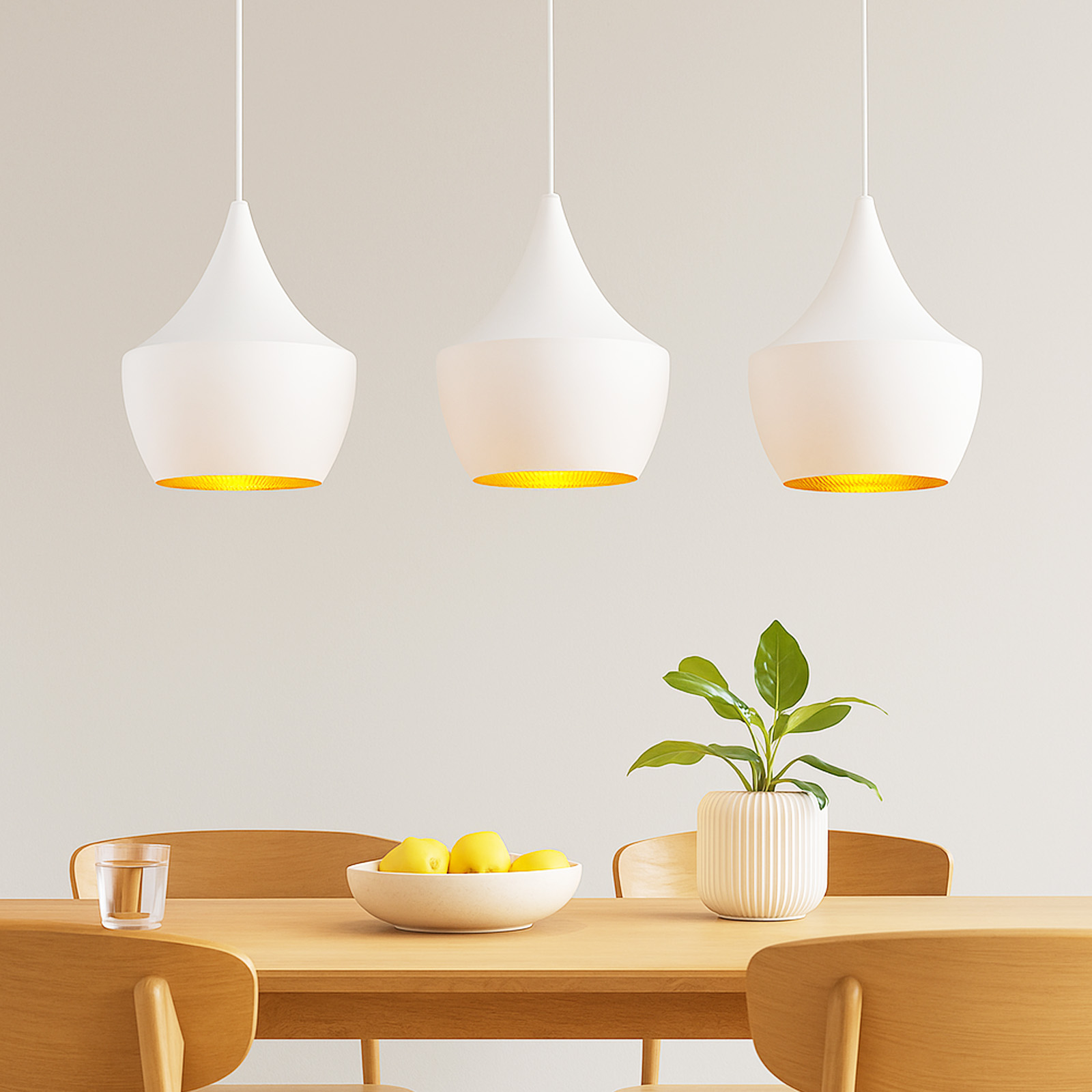 Lámparas colgantes blancas, en forma de lágrima, sobre mesa de madera con fruta y planta.