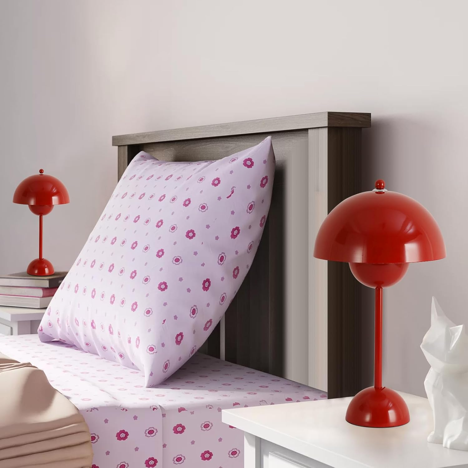 Escena de dormitorio: Lámparas de mesa rojas, una cama con sábanas y almohada estampadas florales.