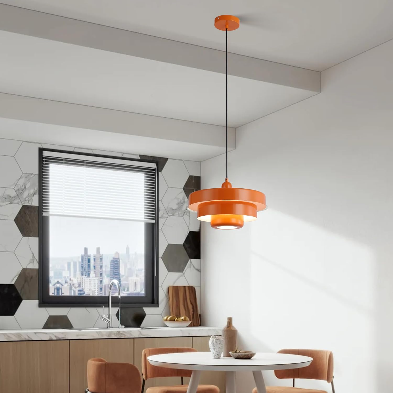 Lámpara colgante naranja en una cocina. El aparato tiene un diseño escalonado y cuelga sobre una mesa.