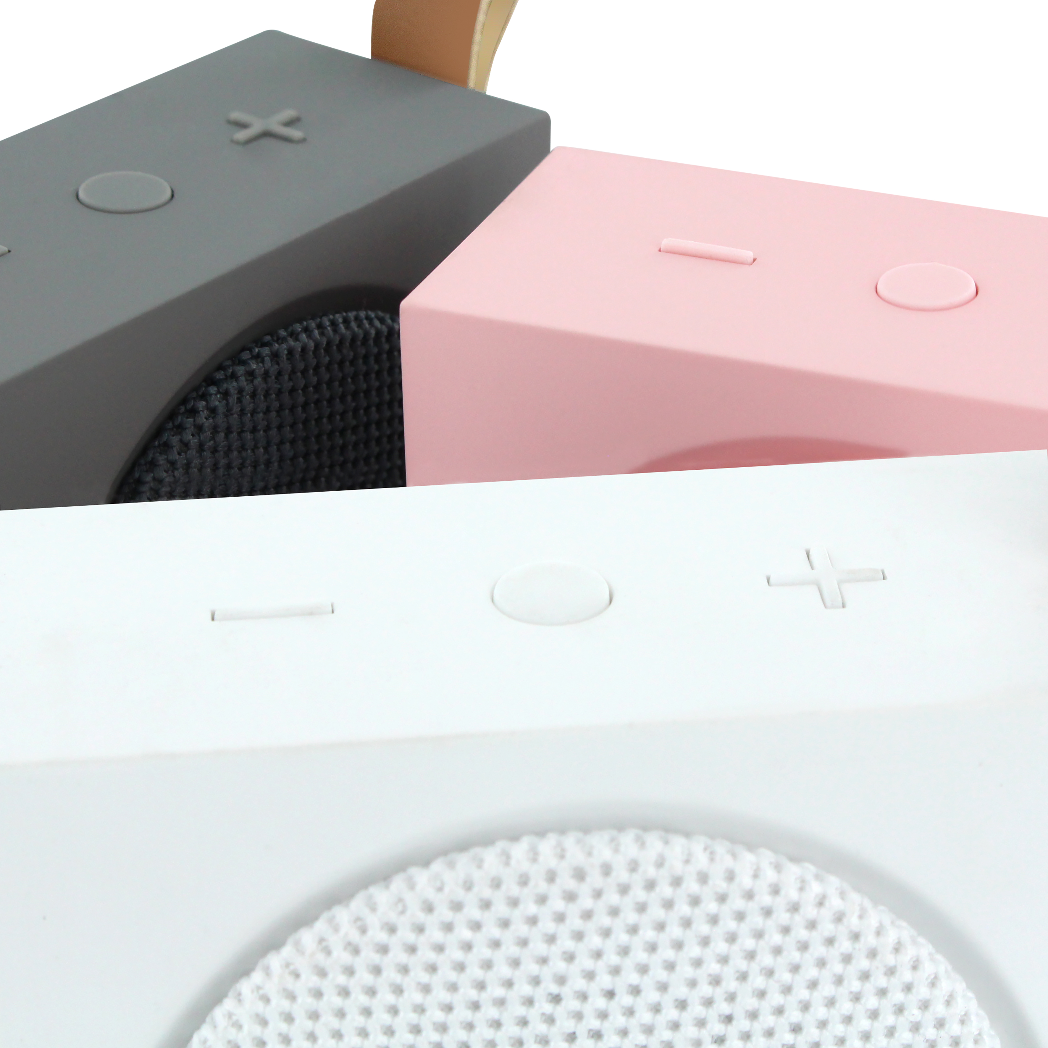 Primer plano de tres altavoces en gris, rosa y blanco. Cada uno tiene un botón diferente y una malla de altavoz visible.
