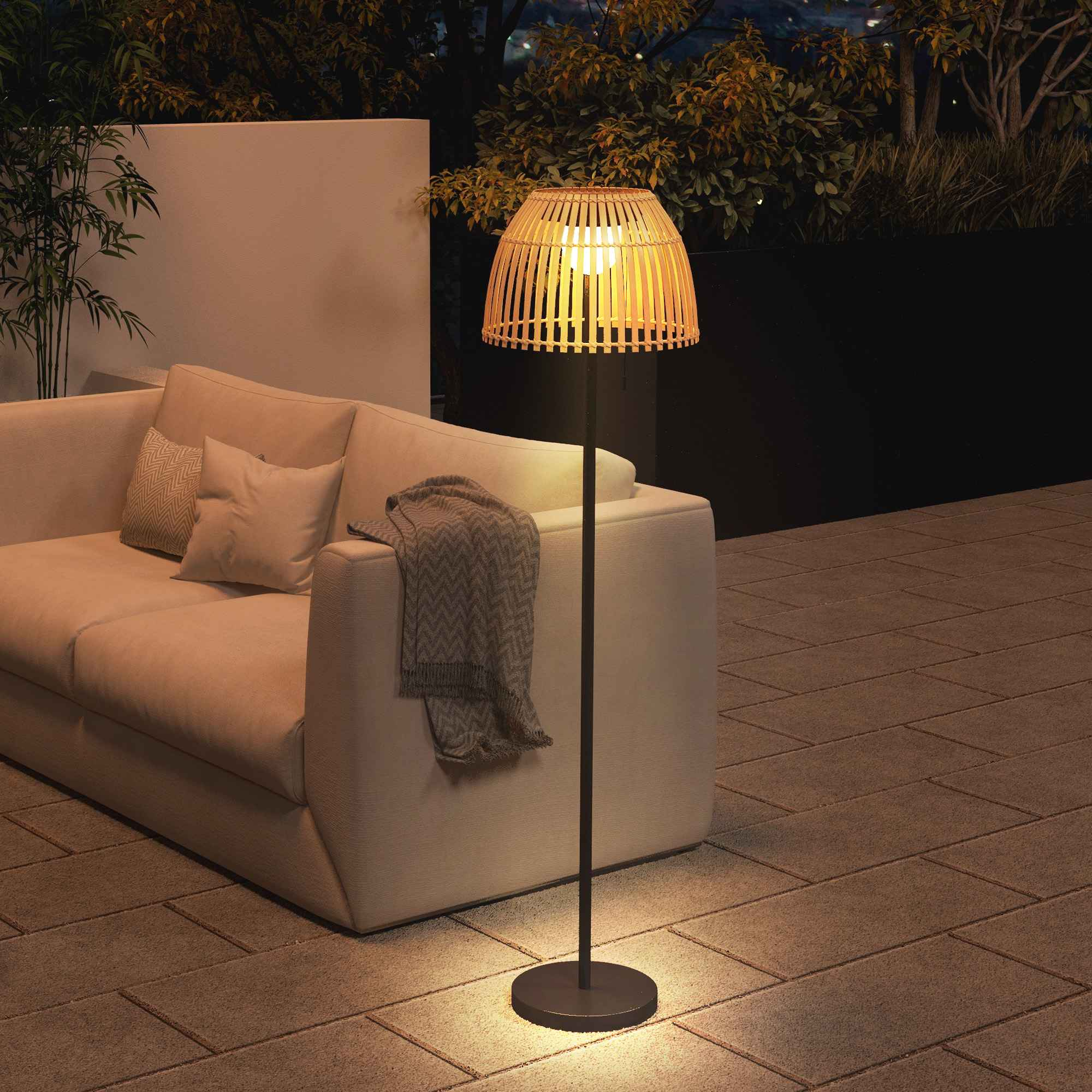 Eine Stehlampe auf einer Terrasse. Es gibt ein Sofa und einige Kissen. Der Hintergrund ist dunkel.