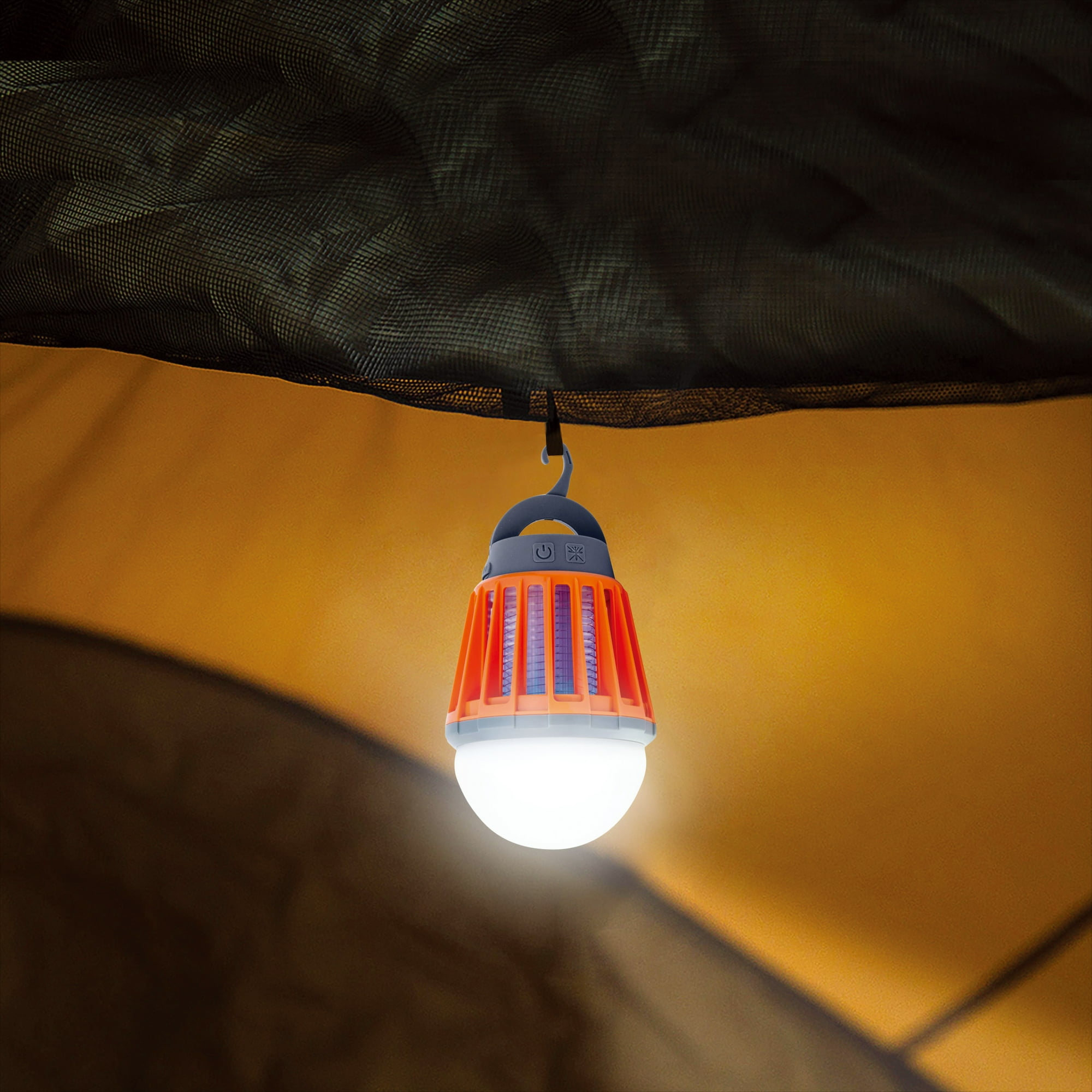 Ein hängender Insektenvernichter in einem orangefarbenen Käfig mit weißem Licht, von innen in einem Zelt gesehen.