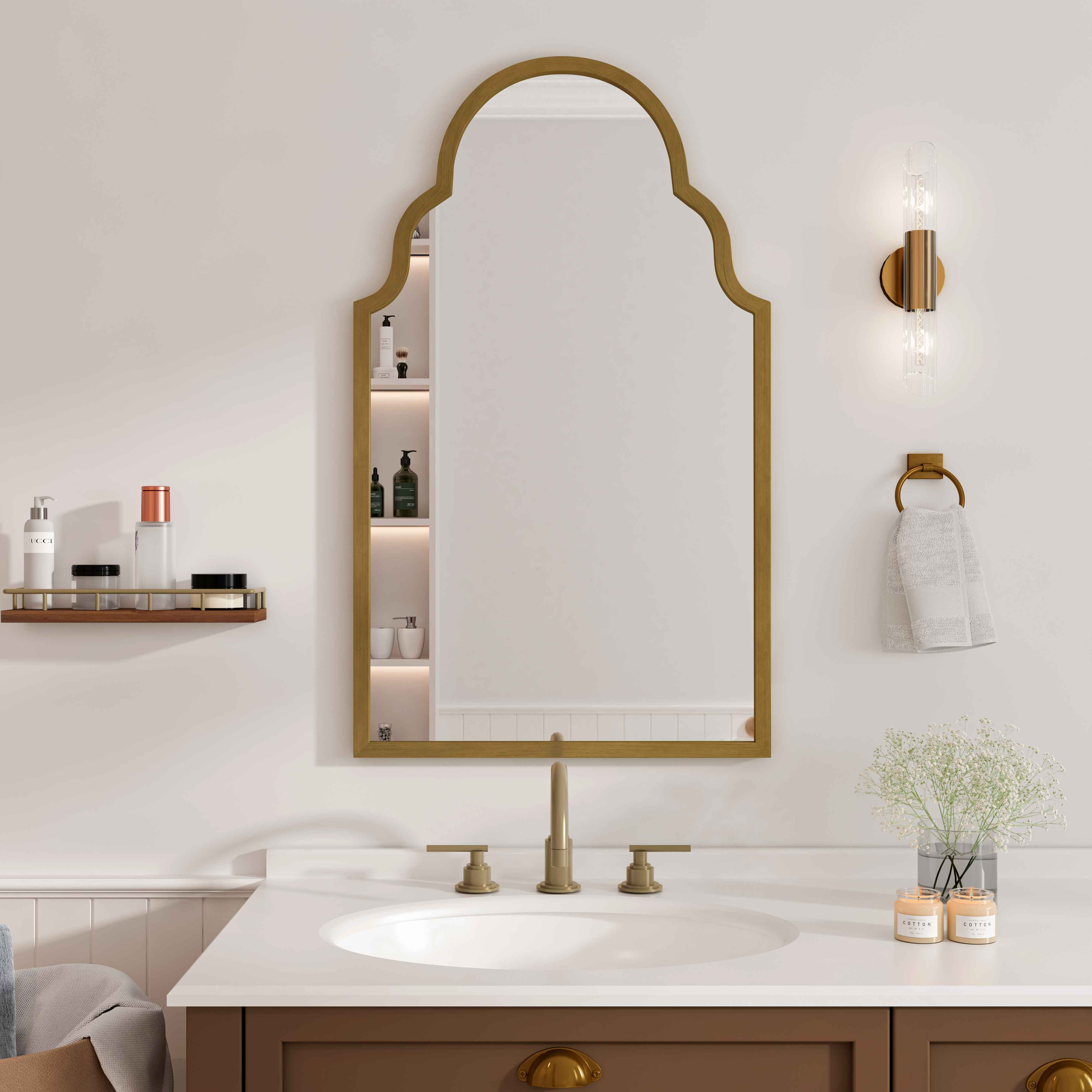 Ein Badezimmer mit goldgerahmtem Spiegel, Regalen mit Produkten, einem Waschbecken und einem braunen Schrank. Ein Handtuch und Blumen sind ebenfalls vorhanden.