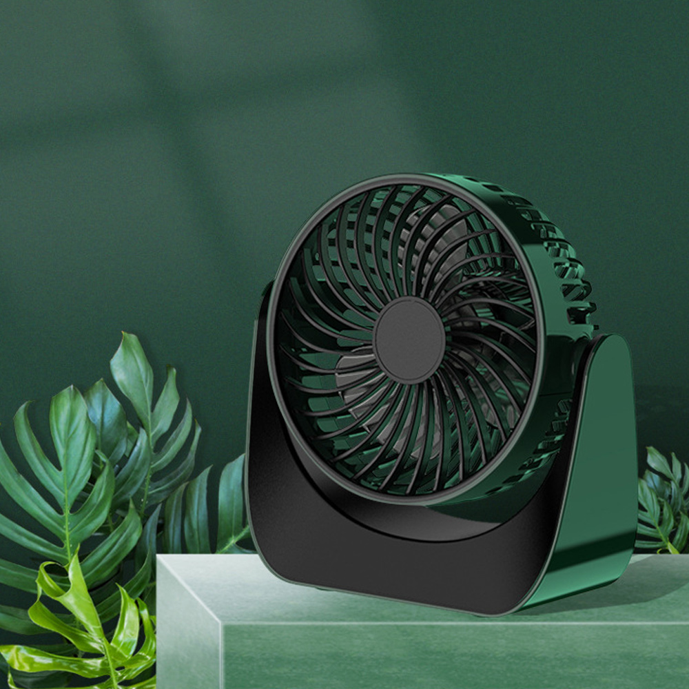 Grüner Schreibtischventilator auf grüner Oberfläche mit dunkelgrünem Hintergrund.