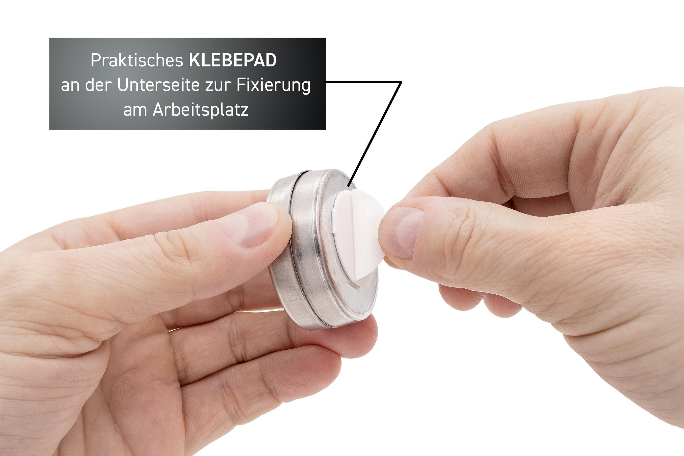 Hände halten einen runden Metallbehälter und bringen ein Klebepad an. Text steht über dem Behälter.