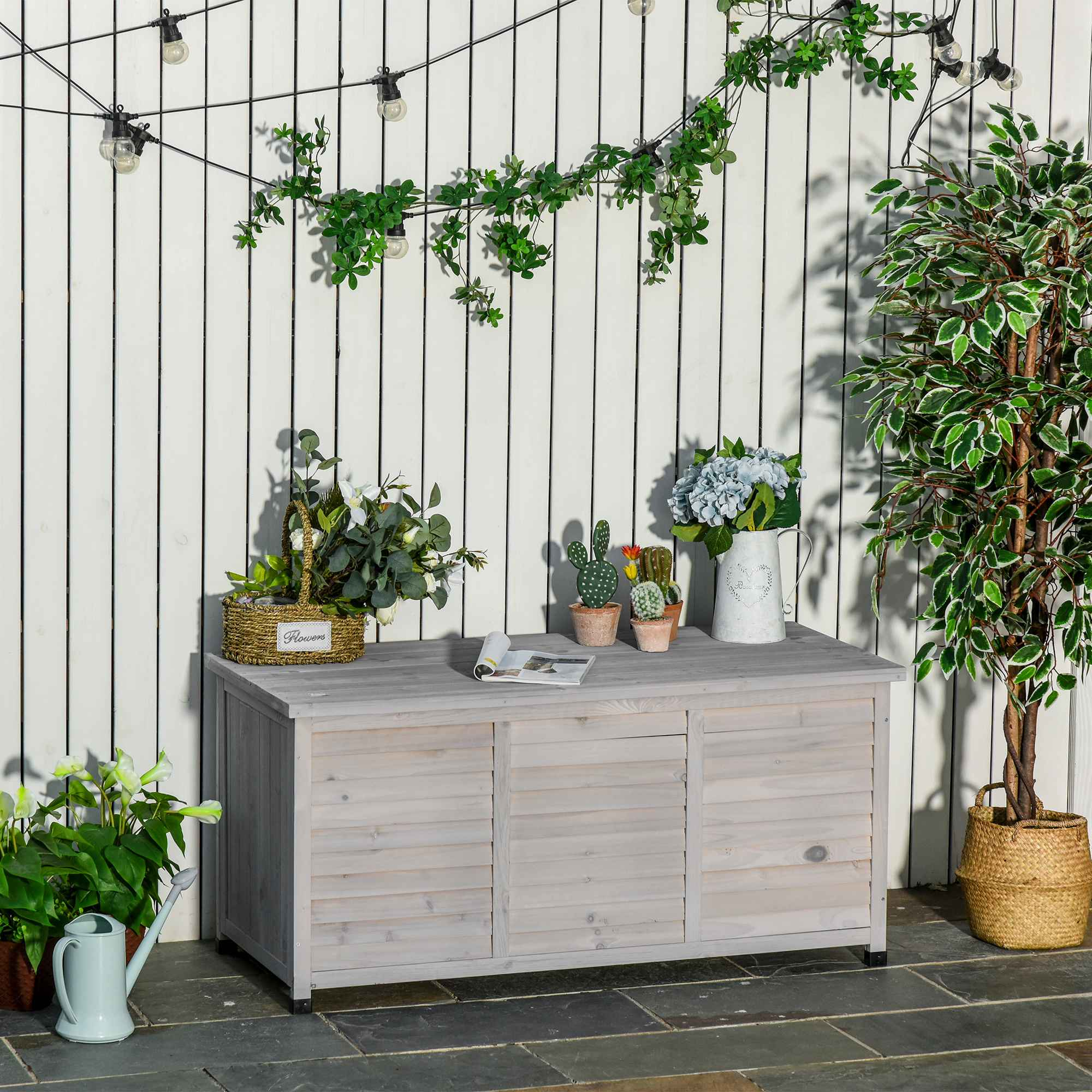 Eine weiße Gartenbank mit Lattenfront, umgeben von Pflanzen und dekorativen Gegenständen.