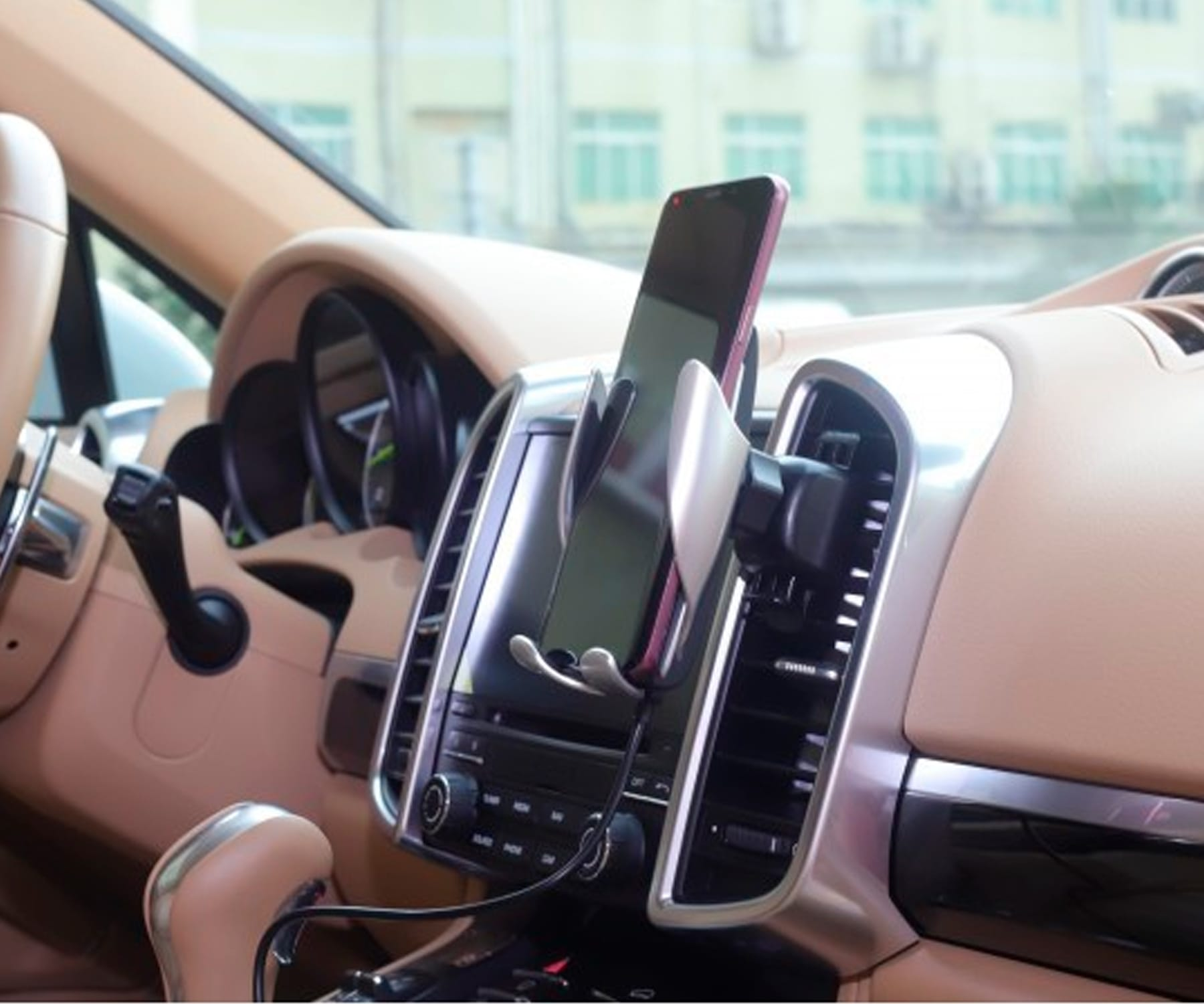 Un telefono è montato in un supporto per auto sul cruscotto. Il supporto è argento e nero.