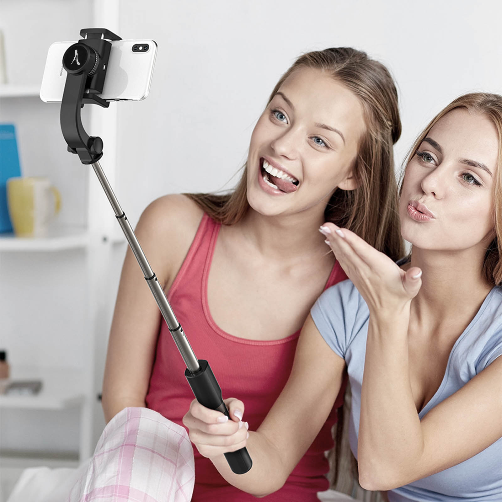 Dos mujeres jóvenes tomándose un selfie con un palo selfie. Una hace una mueca.
