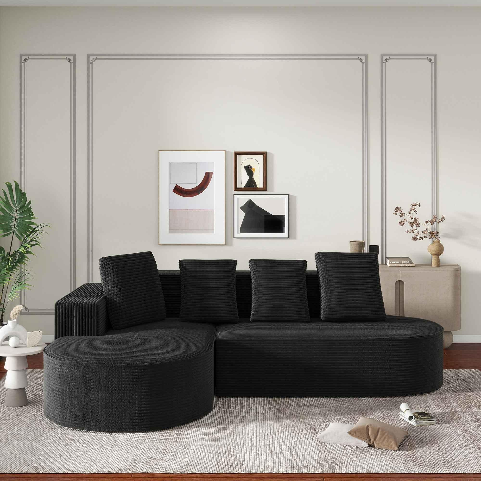 Schwarzes Ecksofa mit mehreren Kissen, vor einer Wand mit gerahmten Kunstwerken und einem Beistelltisch.